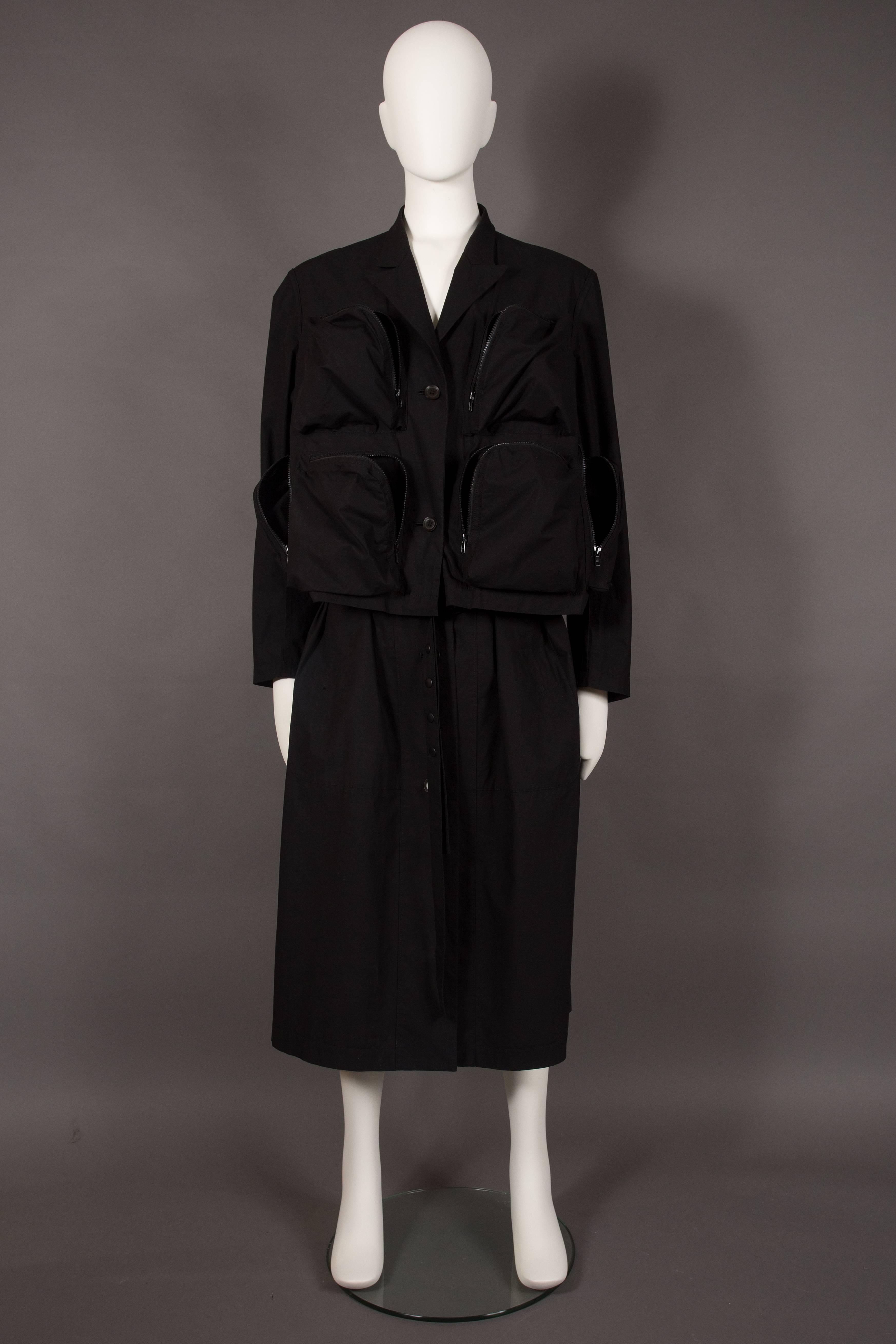 A rare runway Yohji Yamamoto POUR HOMME oversized military coat, spring-summer 2006. 

Six oversized zippered pockets on the bodice, pointed lapels, back slit on the center seam, multiple snap button closures on belt, interior belt with plastic