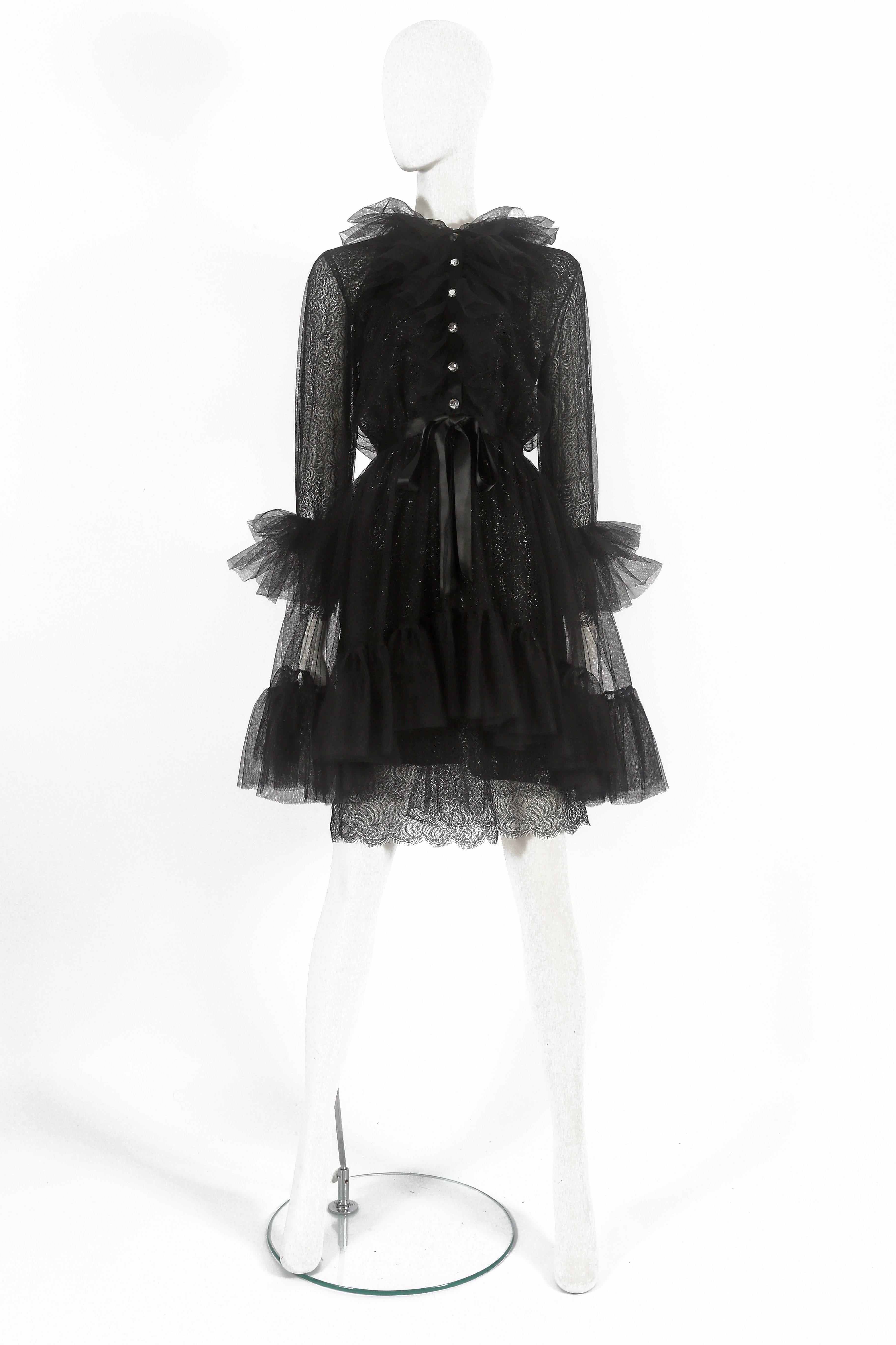 Exquisite and rare Yves Saint Laurent cocktail dress, circa 1980. The dress features two layers of lace, tulle overlayer with ruffled skirt, cuffs and collar, rhinestone buttons, silk bow fastening and attachable silk slip. 