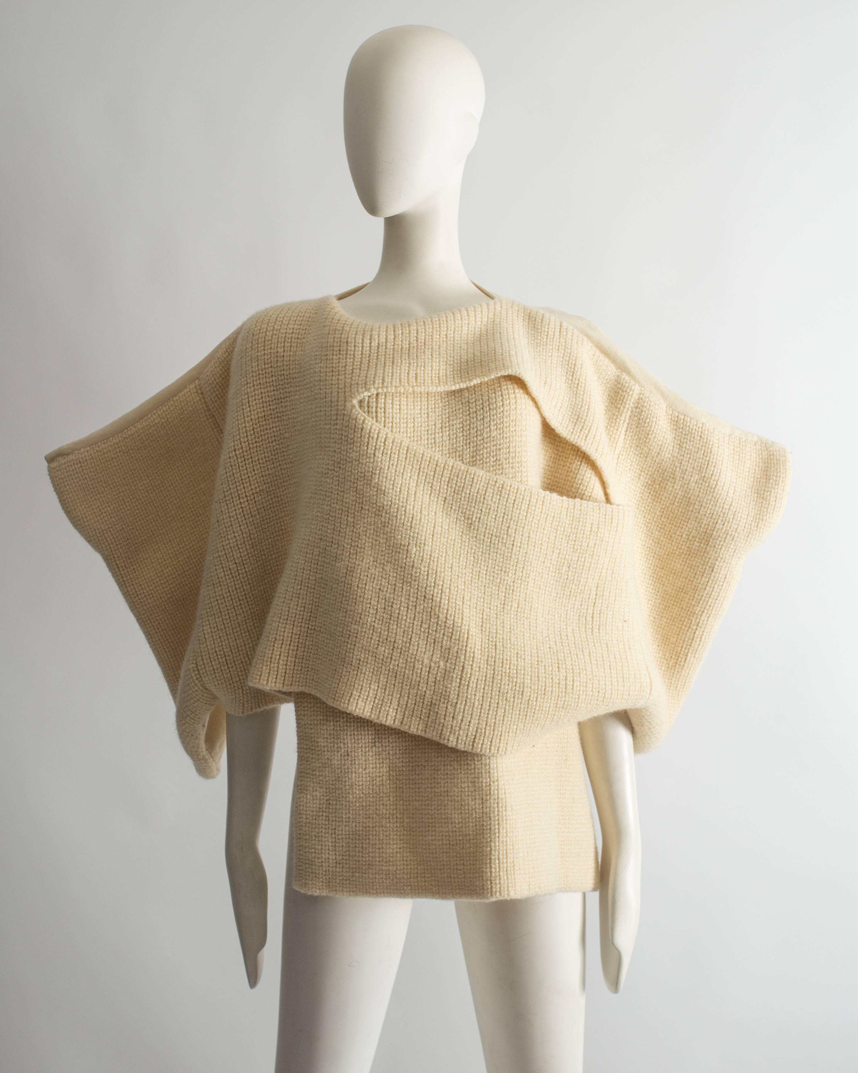 Important Comme des Garcons TRICOT ivory knitted sweater, Autumn-Winter 1983. 

Rectangular form with the back panel of plain-weave wool, the front of double layered stocking stitch with one large intentional slash, with slits for the arms and neck.