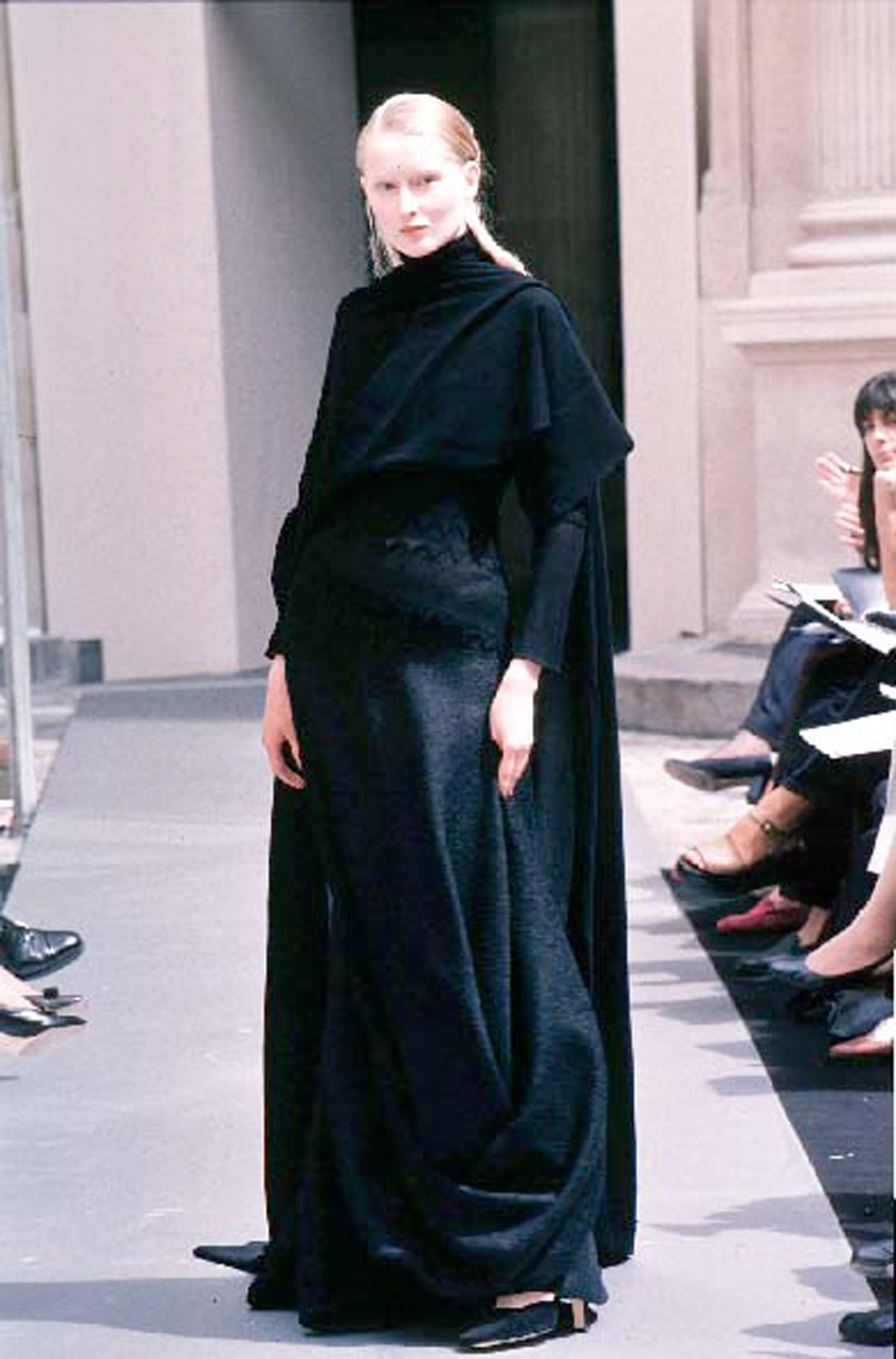 Wir präsentieren ein außergewöhnliches Stück aus der Haute Couture-Kollektion Herbst-Winter 1998 von Ocimar Versolato: das Abendkleid aus schwarzer Bouclé-Wolle und gestrickter Spitze, eine wahre Verkörperung des visionären Ansatzes des Designers in