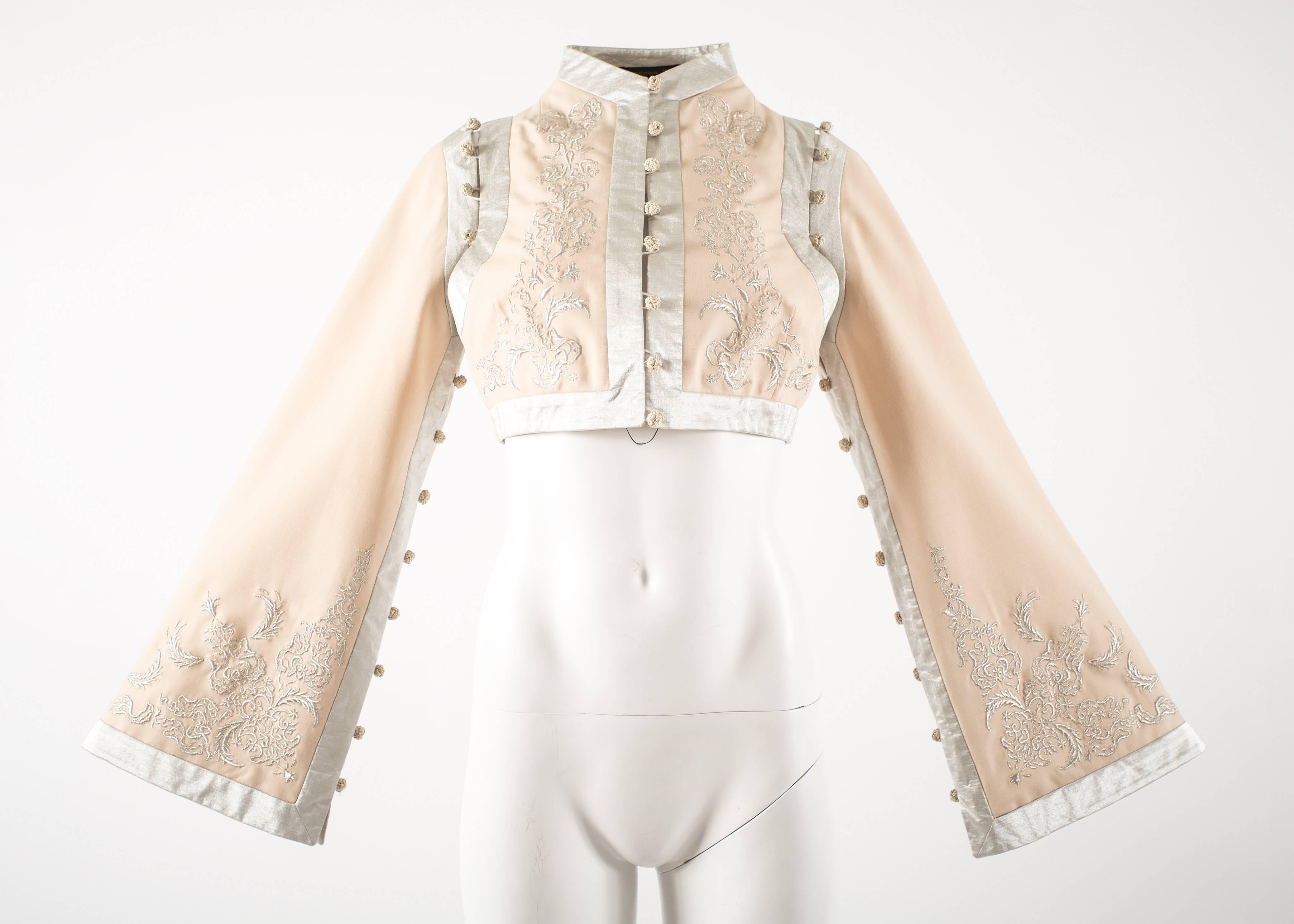 Introducing the archival Alexander McQueen Spring-Summer 2000 ivory silk cropped jacket, a stunning and timeless piece from the late designer's iconic collection.

This exquisite jacket features metallic embroidery, adding a touch of opulence and