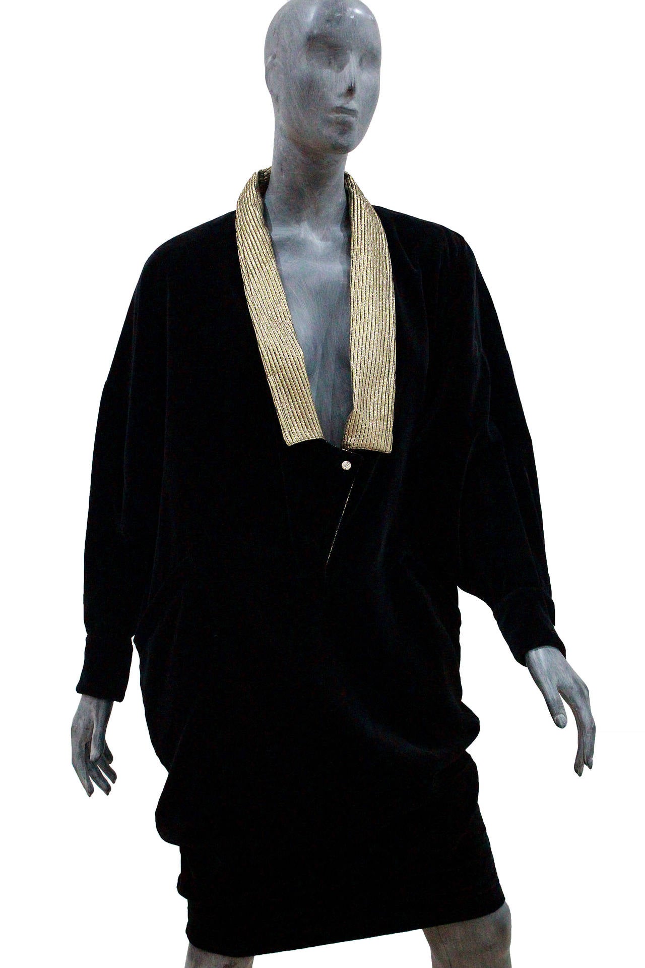 This is a classic Gianni Versace dress made from black velvet with a low plunge neckline, metallic gold collar and diamante buttons on collar and cuffs. 

1980s

Size 42