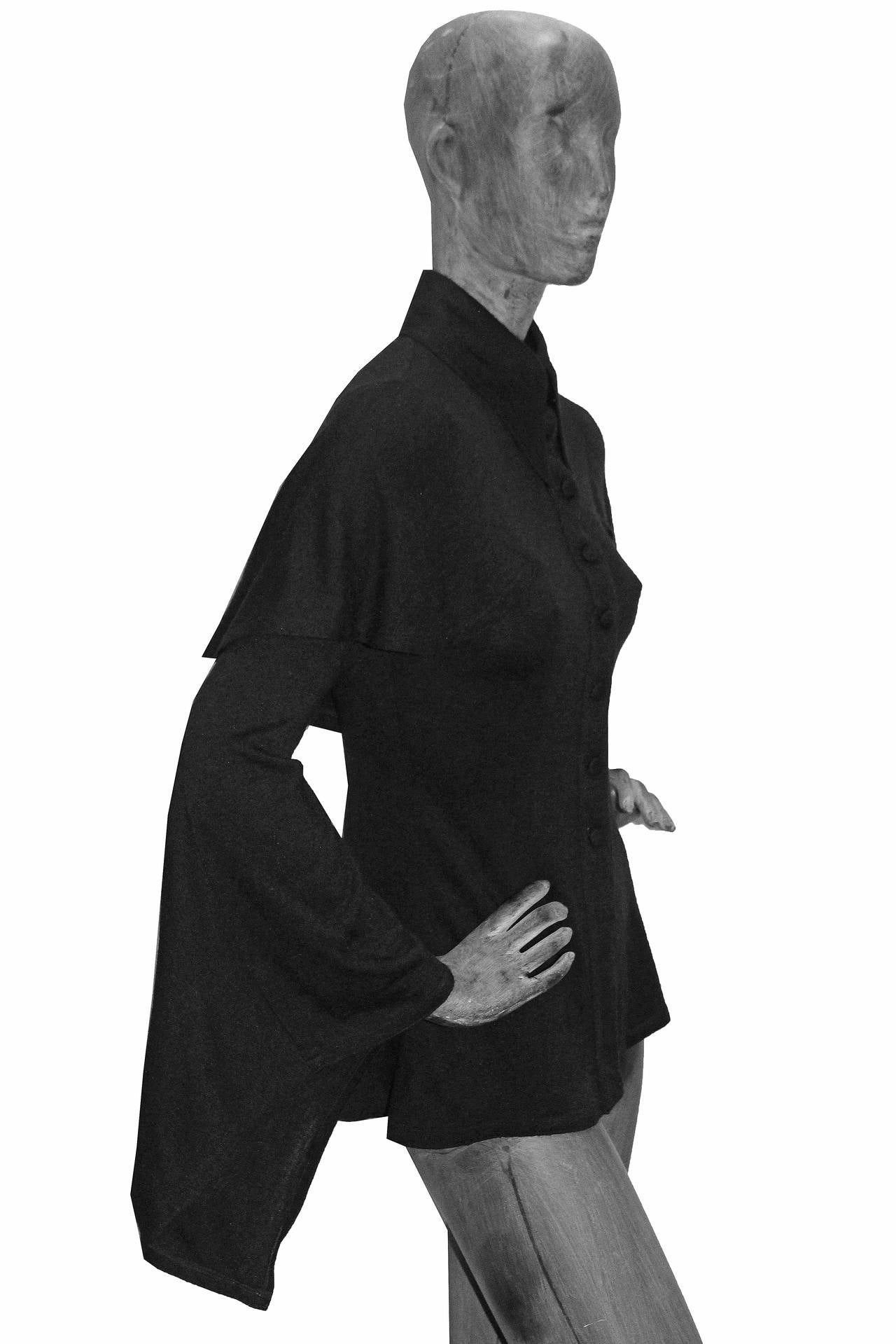 A 1969 Ossie Clark black wool blouse features a pointed collar, fabric button closure, cape and bell sleeves.