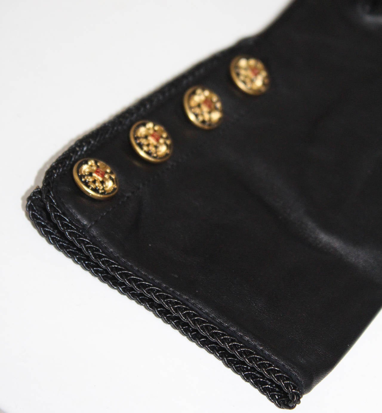 A pair of black lambskin leather Chanel gloves with braided trim and four gold 'cc' buttons. 

Size: 7.5