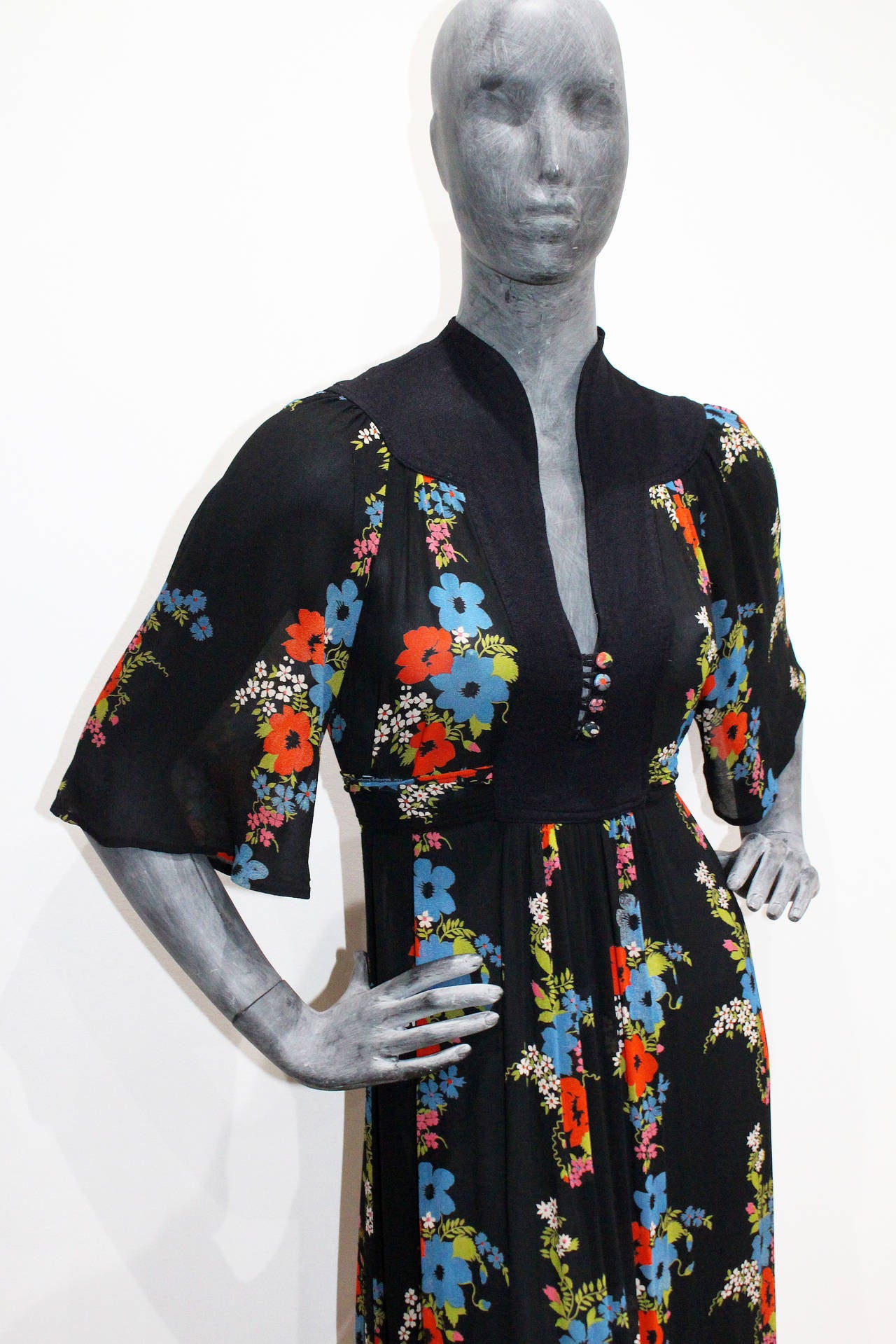 An Ossie Clark for Radley floral printed chiffon dress, circa 1977, labelled and size 10, smock-style bodice with deep yoke,  fabric printed buttons and waist ties, the black ground with floral repeats, bust approx. 86 cm, 34 