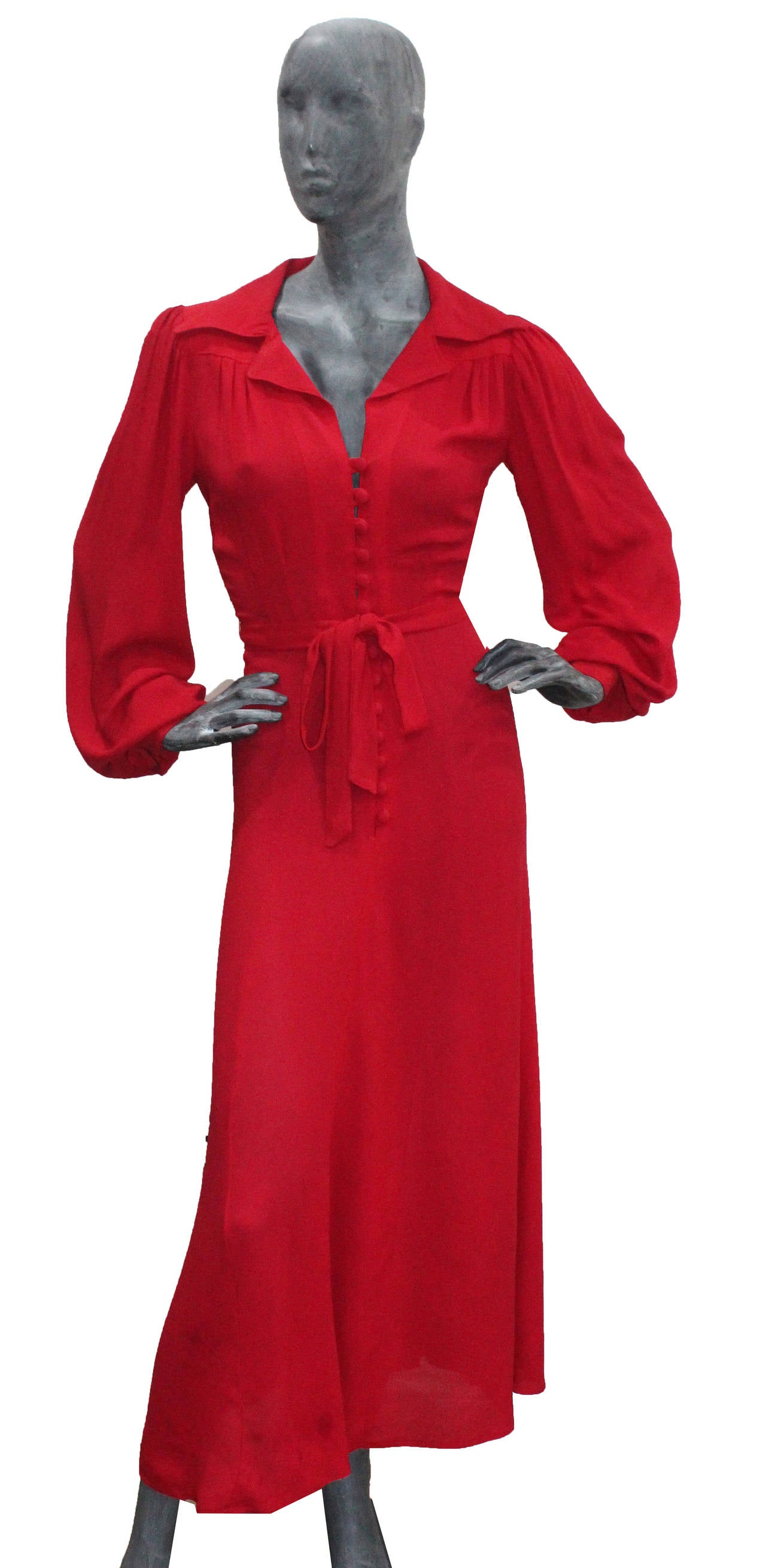 This is the 'Rockstars girlfriend dress' and is the perfect example of Ossie Clarks genius of cutting fabric. The dress is made of red moss crepe fabric and features a 40s inspired pointed collar, low plunge, fabric buttons running from the bust to