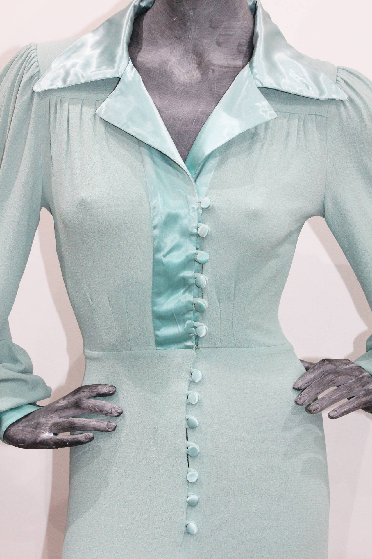 A fabulous dress by the 'King of Kings Road' Ossie Clark. The dress features a pointed satin collar, satin buttons running from the bust to the lower waist, satin cuffs and pleated billowing sleeves. The dress is in a duck egg blue moss crepe. This