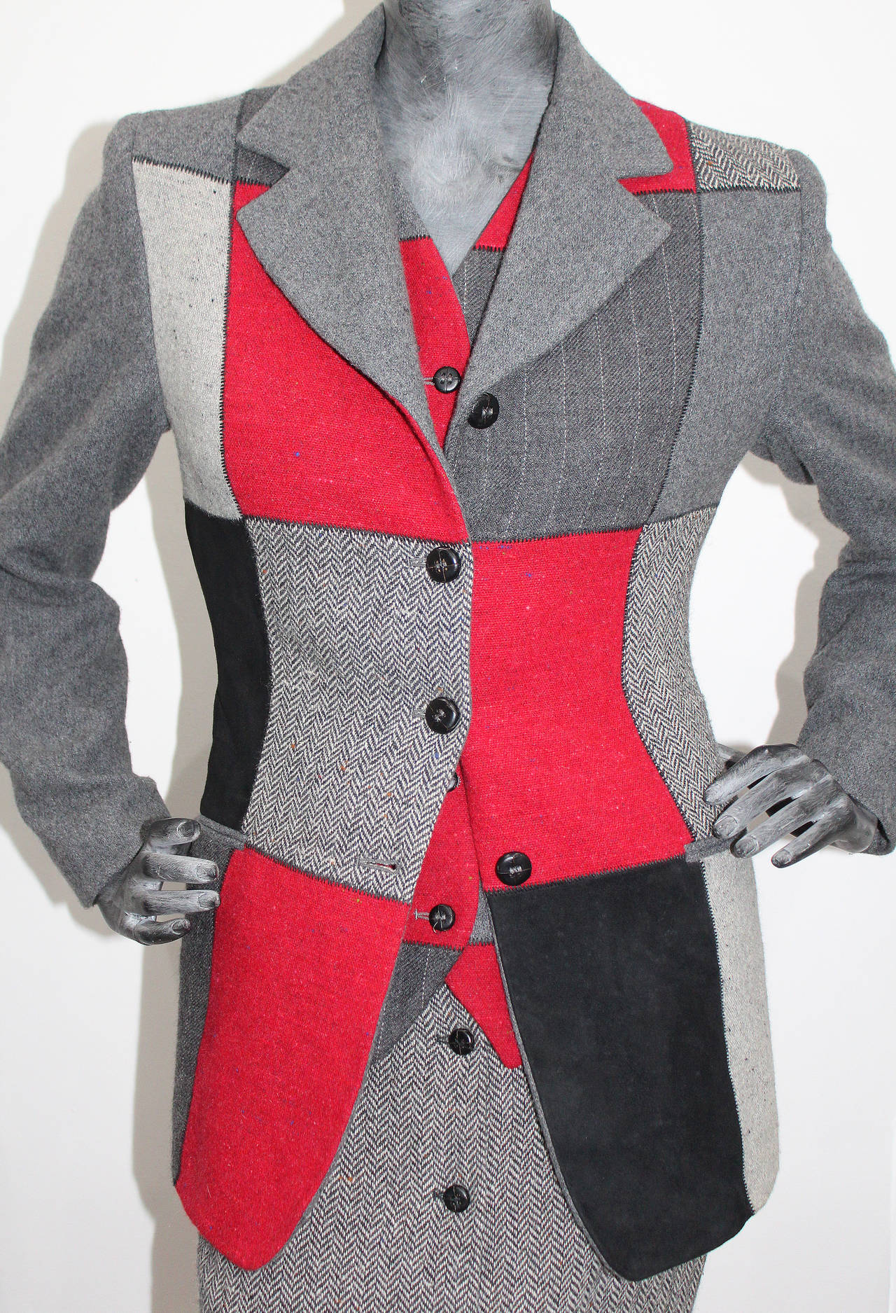 A fine and rare 'WOODY WOODPECKER' Jean Charles De Castelbajac 3 piece tweed skirt suit from 1994. 

The suit features a tailored blazer and waistcoat both in patchwork tweed with black suede assets. The high waisted pencil skirt is in a fine