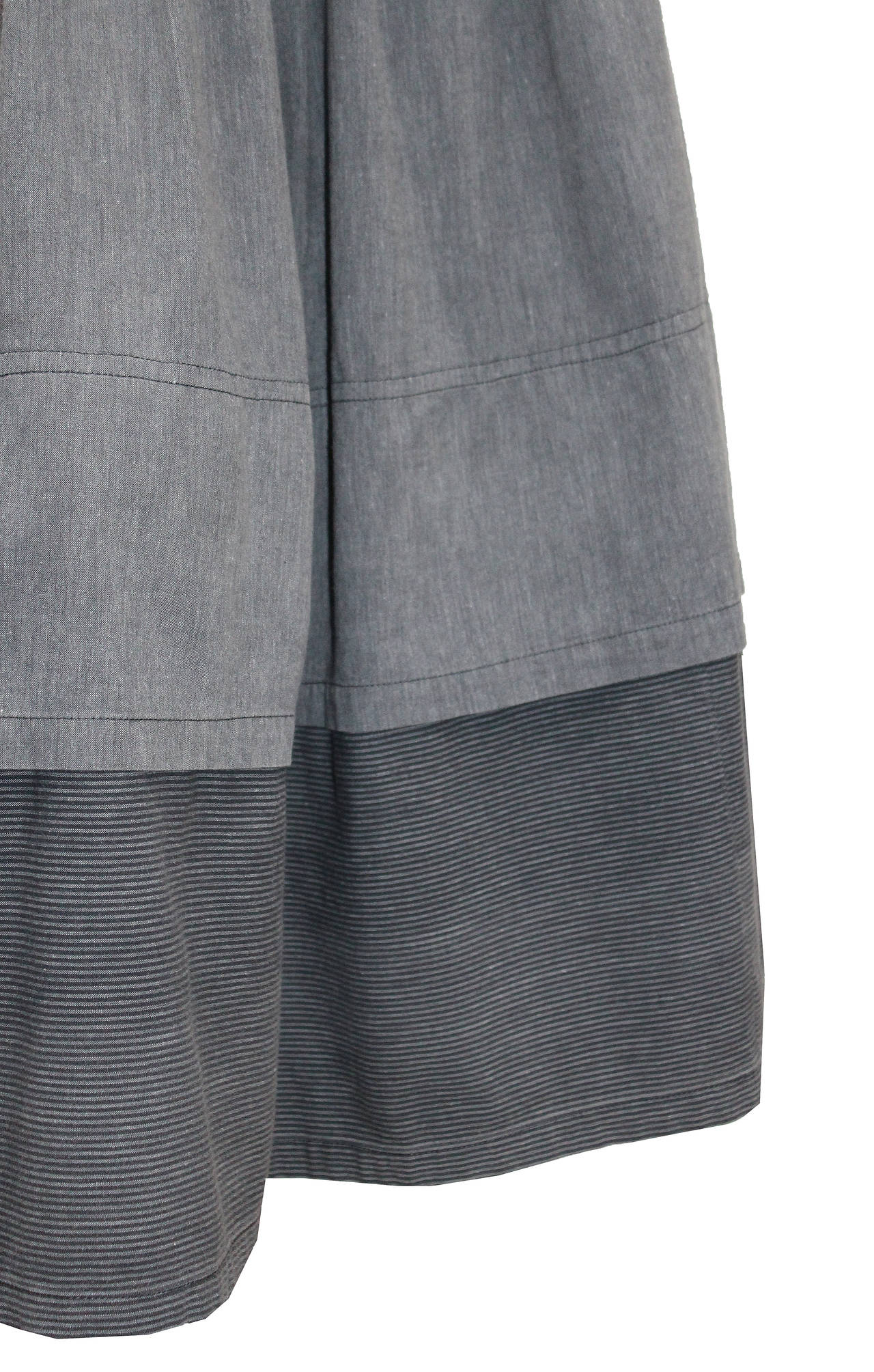 A rare and early ISSEY MIYAKE sports cotton skirt suit from the 1970s. The ensemble includes a high waisted full pleated skirt and a loose fitting blouse with 2 front open pockets and 1 at the rear. The textiles used are 100% cotton and are in a mix