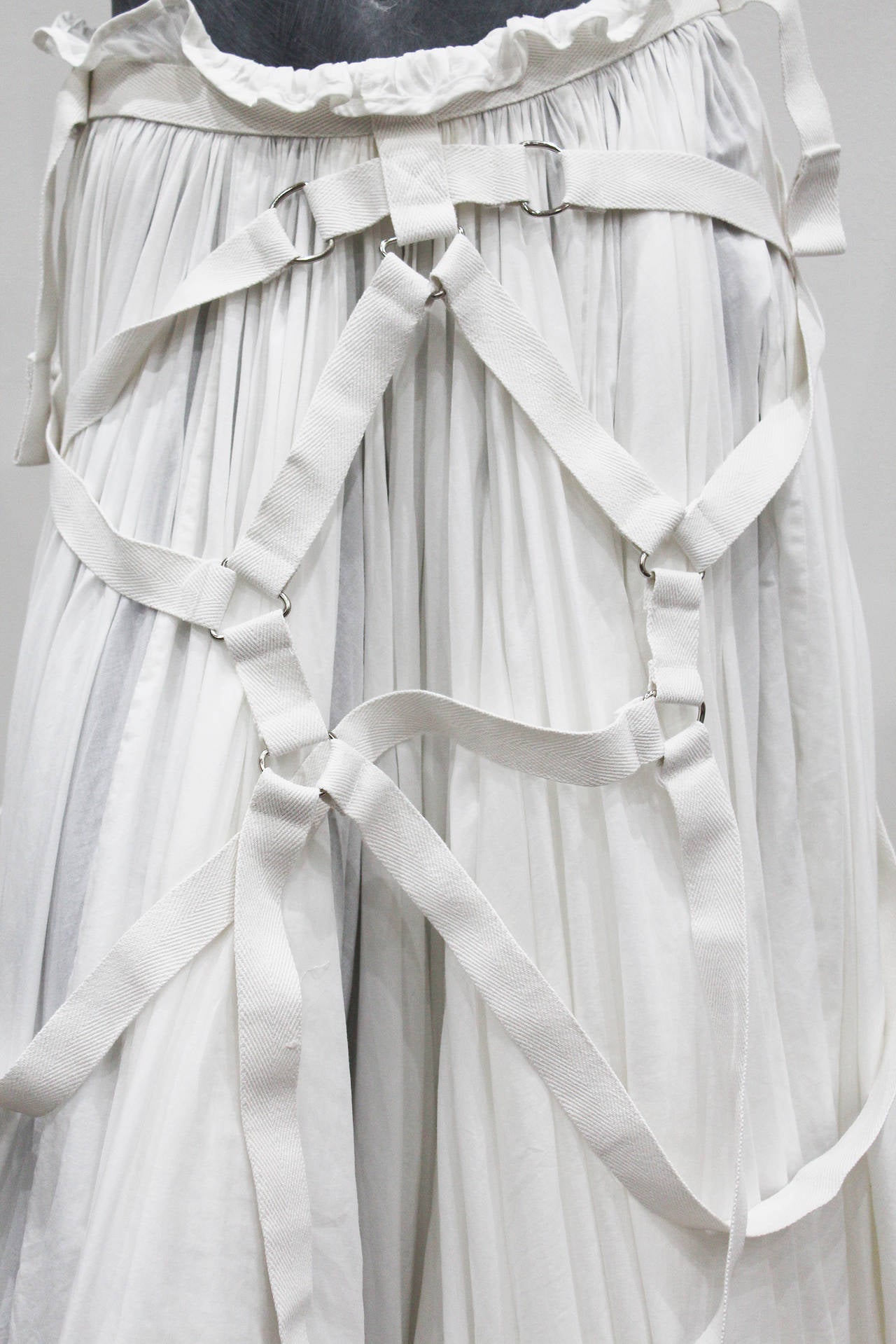 A white cotton full pleated layered skirt by Junya Watanabe for COMME des GARCONS. The skirt was first shown on the Paris runway for the Spring/Summer 2003 collection. The skirt is layered with masses of white cotton and is caged with bondage