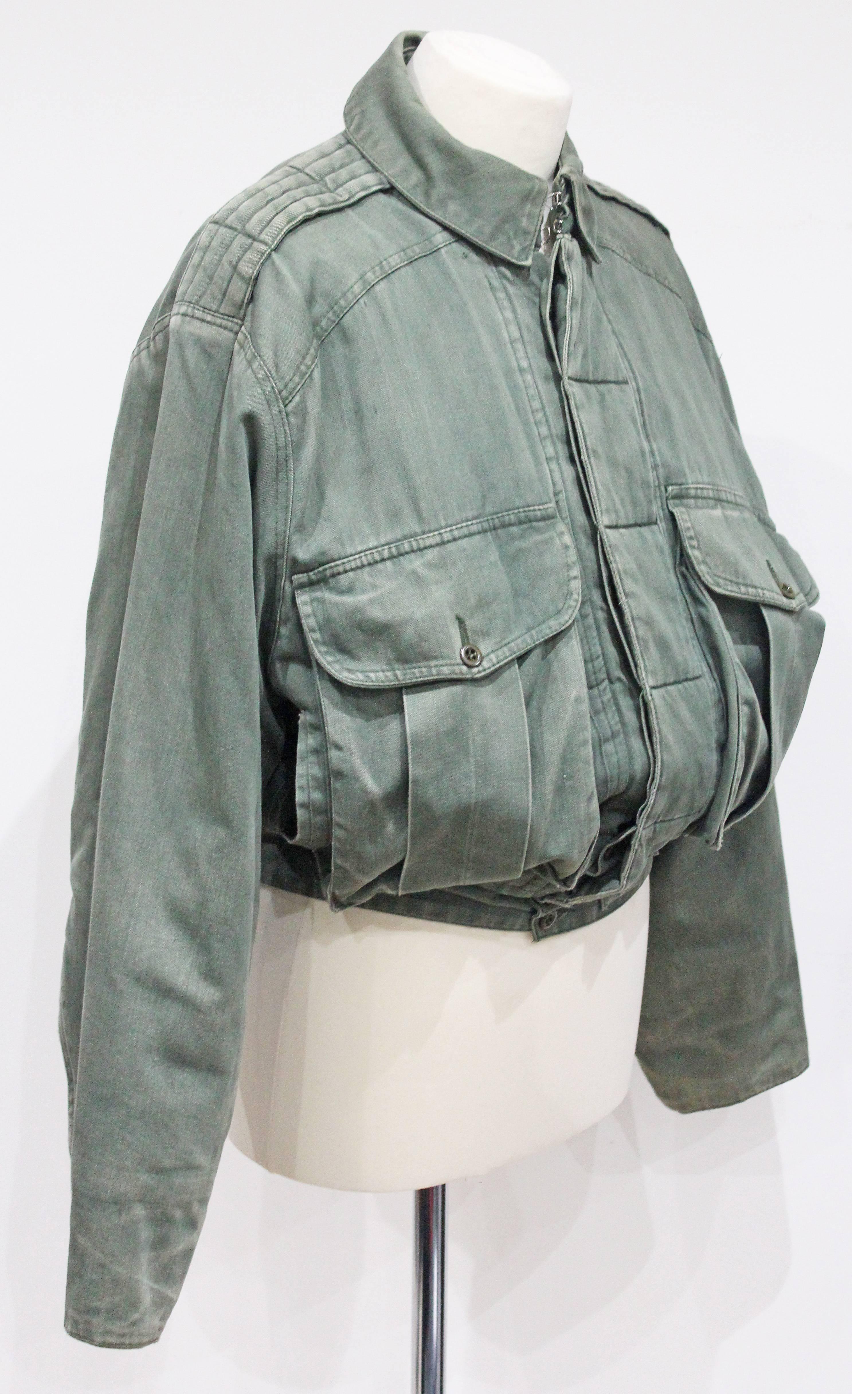 Un raro bomber imbottito di Katharine Hamnett disegnato negli anni Ottanta. La giacca è di colore verde kaki slavato e presenta due grandi tasche anteriori. 

Etichettato 