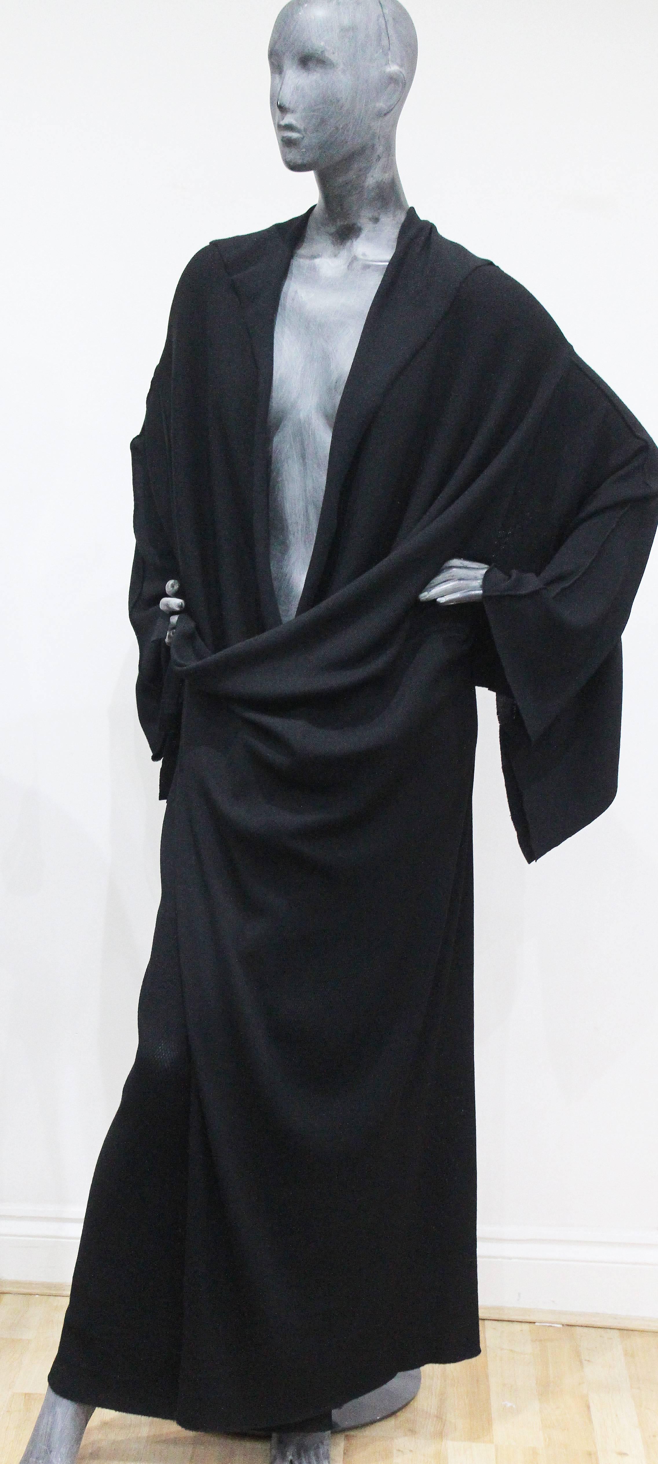 An exceptional Issey Miyake black knitted full length cardigan in a kimono style. The cardigan fastens under both armpits which creates beautiful drapery and a kimono style. The sleeves are very wide and have long raw cut edges as does the collar.