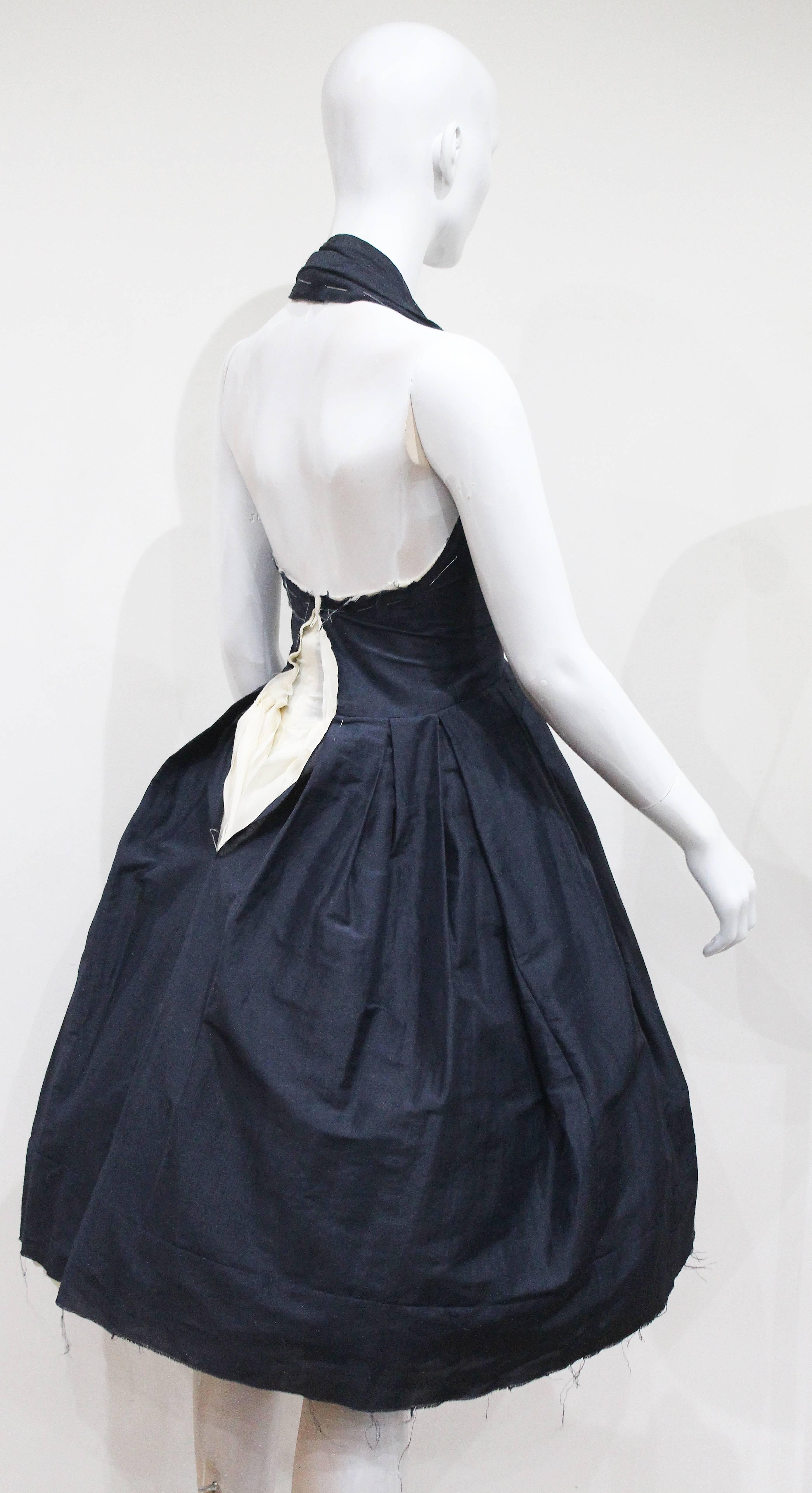 A COMME des GARCONS by Rei Kawakubo de-constructed marine blue halter neck dress with five off-white cotton underskirts, made in the year 1997 for the Spring/Summer 1998 season. The dress has a raw, frayed and uneven finish, balloon layered skirt