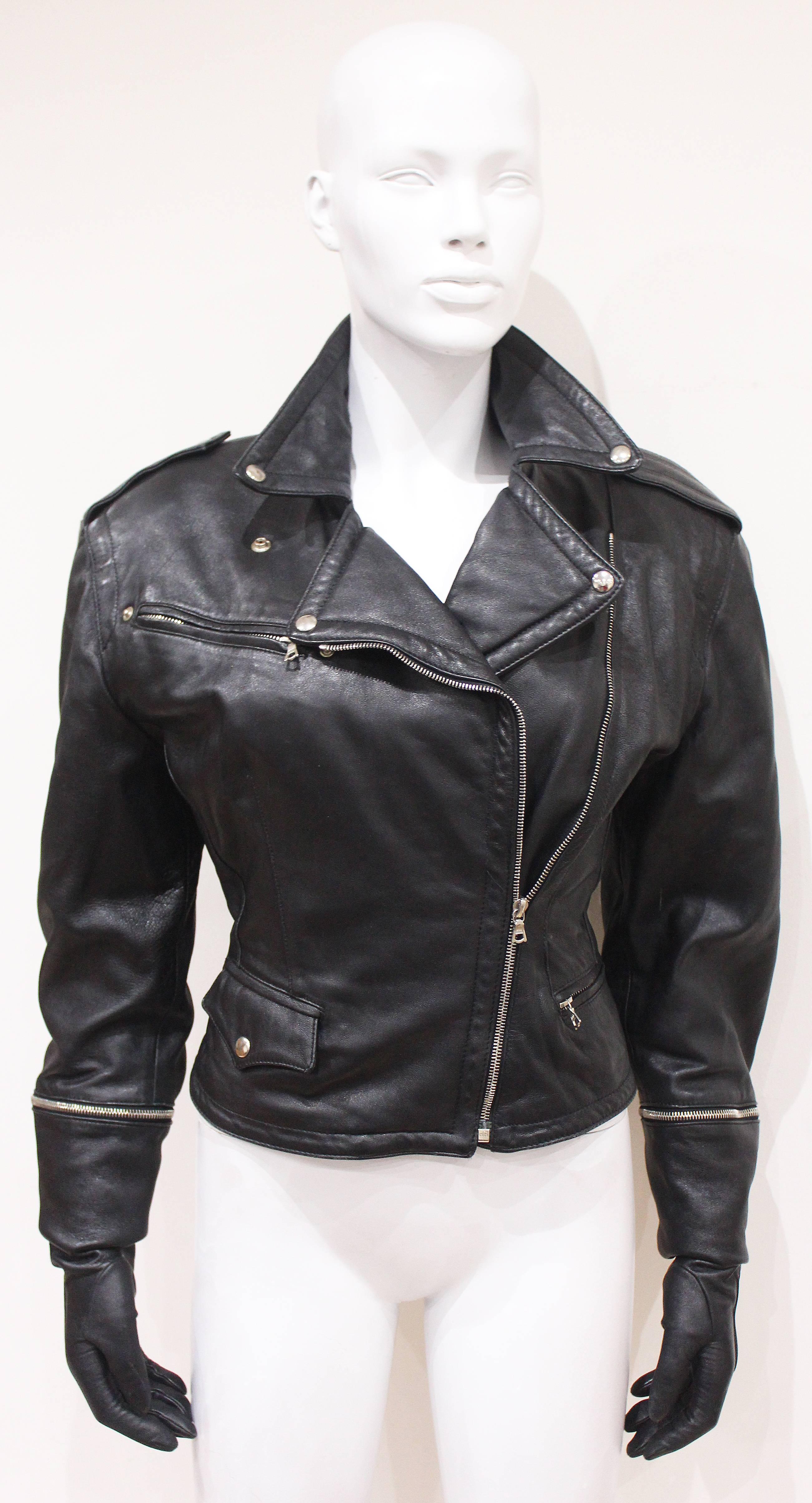 An exceptional and truly one of a kind motorcycle jacket by Josyln Clarke from the 1980s. The jacket is in a classic motorcycle style in black leather but extremely high fashion with the detachable leather gloves. The jacket has metal silver zippers