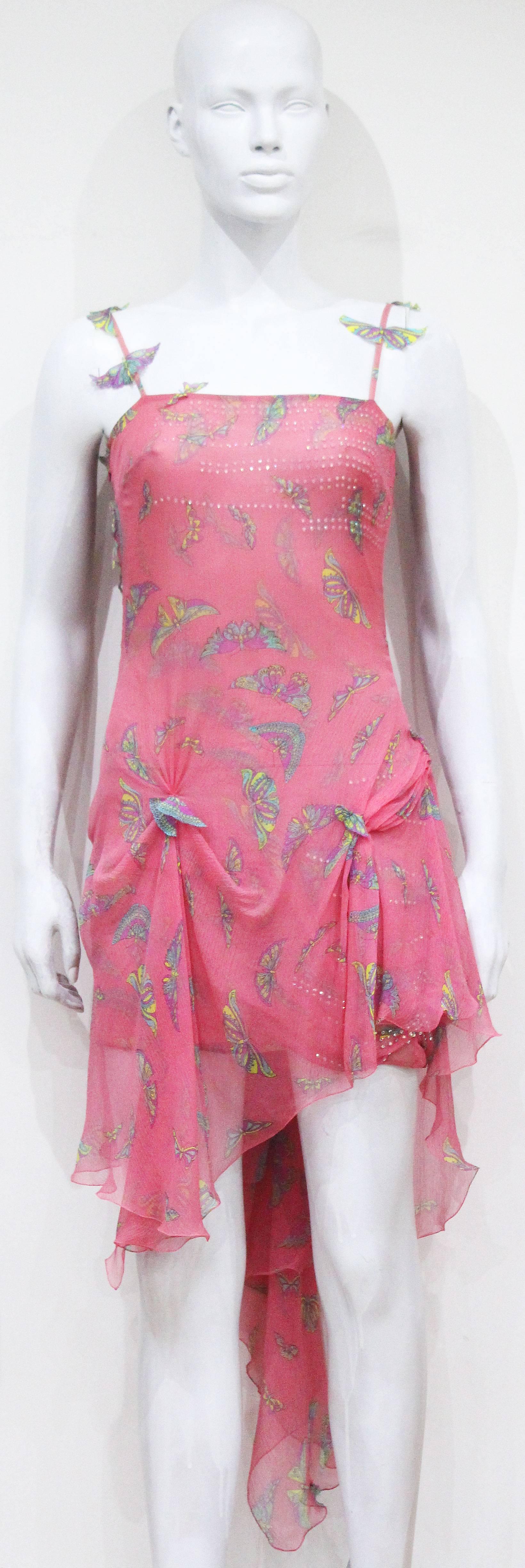 A Gianni Versace pink silk chiffon evening dress from the 1990s. The dress features 3-D cut out chiffon butterflies throughout, butterfly print with with pink base, diamante embellishment on bust and long train at rear. 

Fr 38 - It 42 