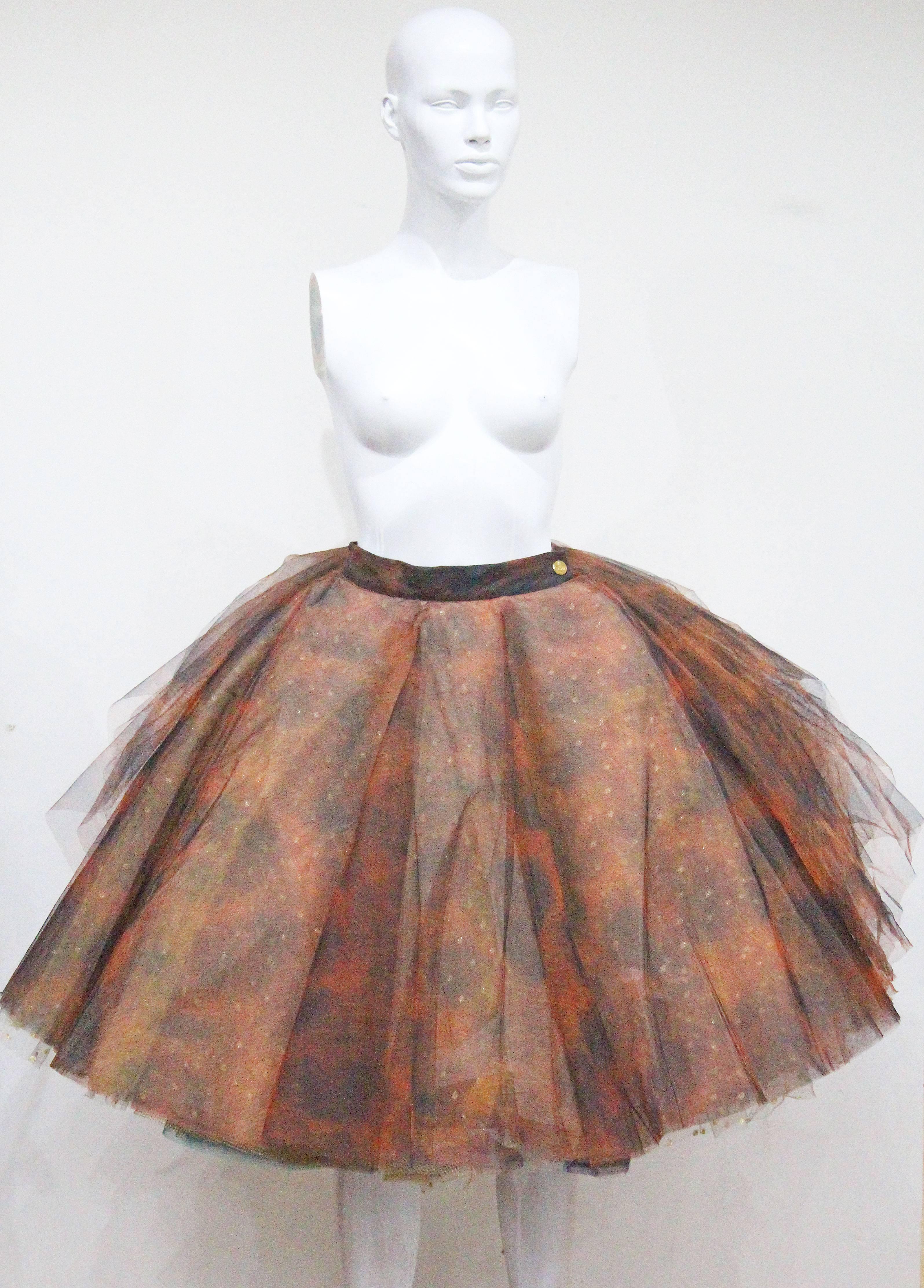 A museum worthy Vivienne Westwood tulle skirt from the year 1993. The skirt has various layers of netted tulle in a ray of colours and prints. The skirt lowers at the front gradually getting shorter towards the rear leaving the layers fully exposed