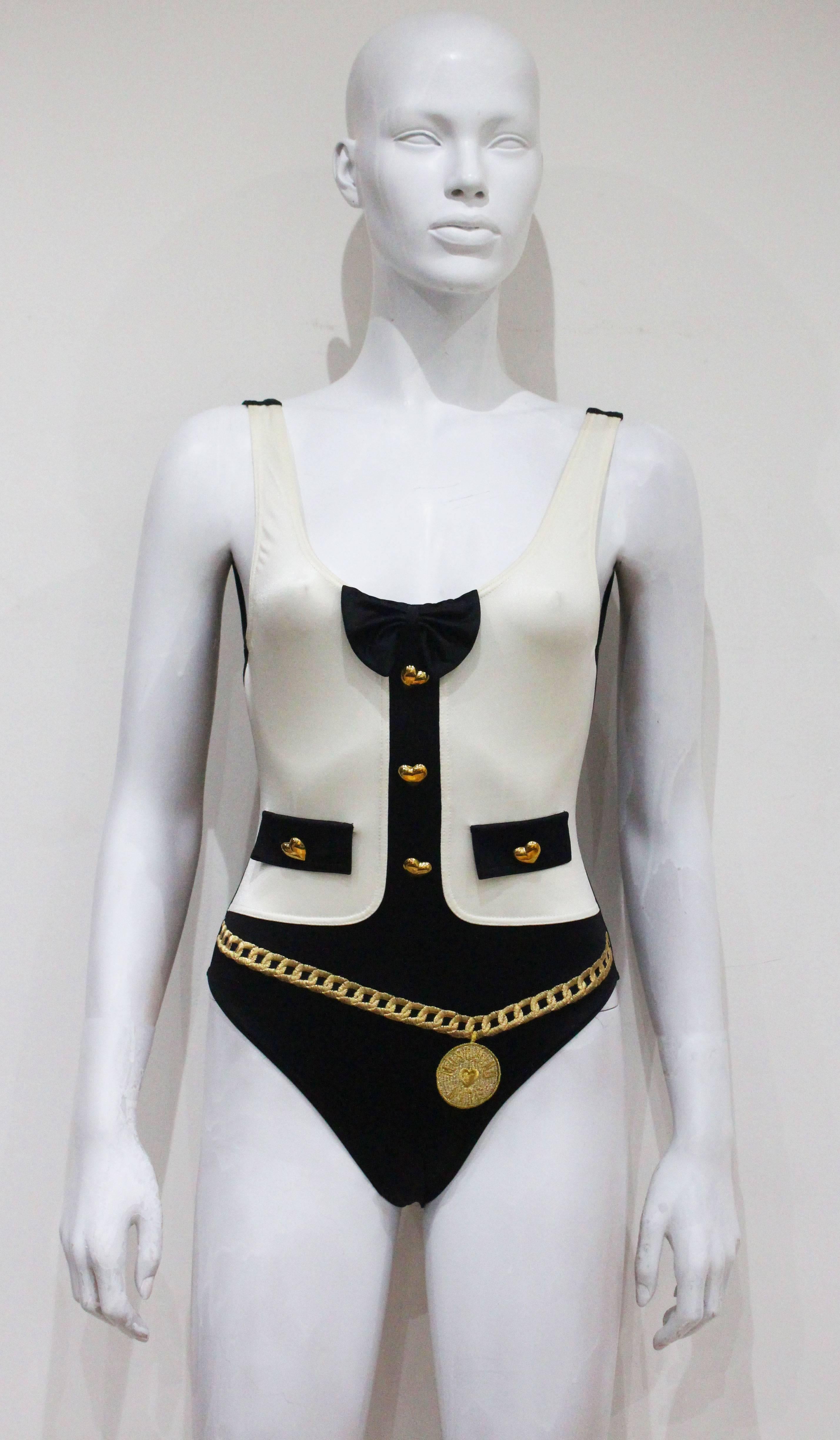 A rare Moschino leotard from the 1990s. The leotard features an embroidered gold Moschino chain, gold heart buttons and attached bow tie.

Italian 40 / French 36 / UK 8