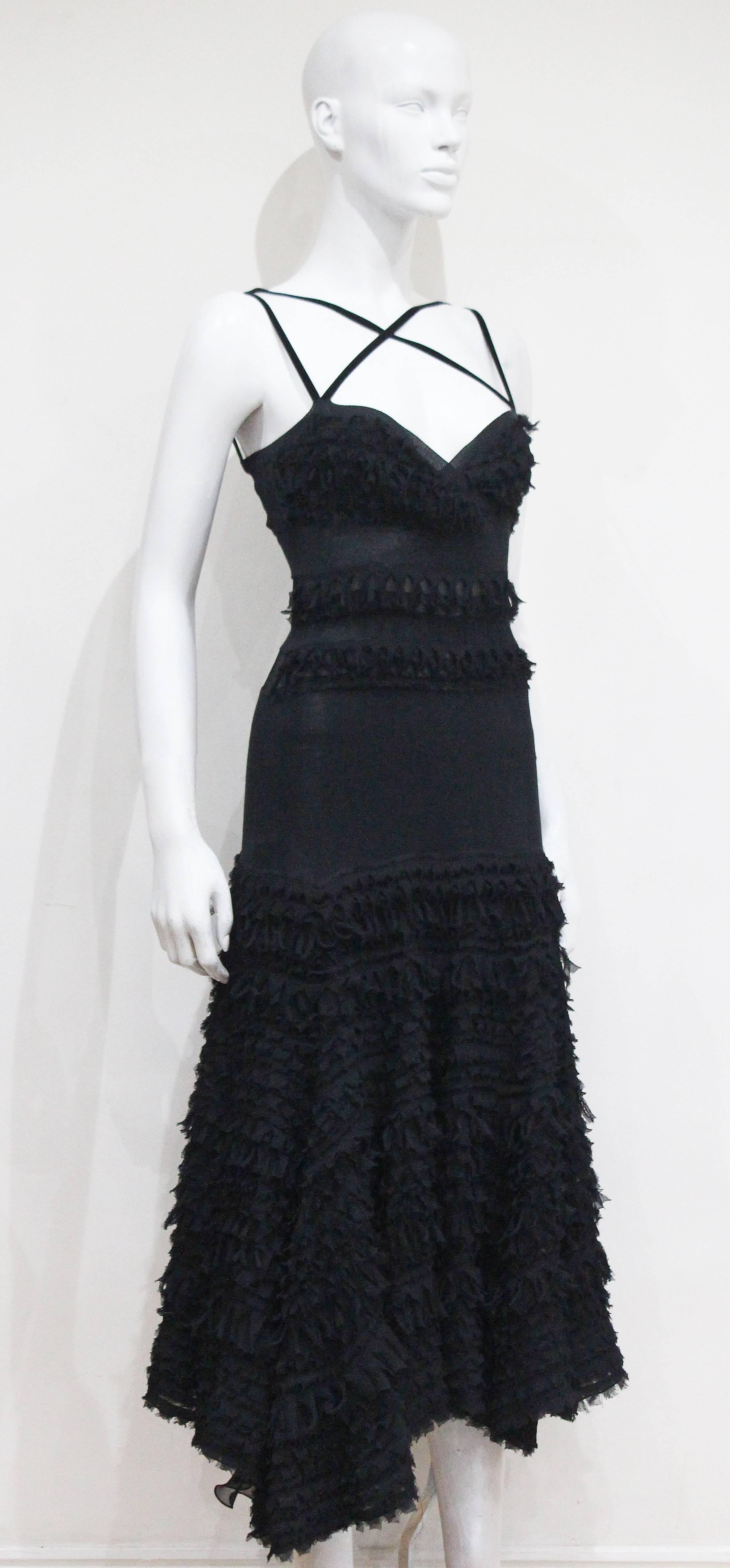 A Prada black silk evening dress from the 1990s. The dress has cross over straps at the front, sheer panels at the rear, drop waistline and a layered silk chiffon skirt. 

It 40 - Fr 36 - UK 8 