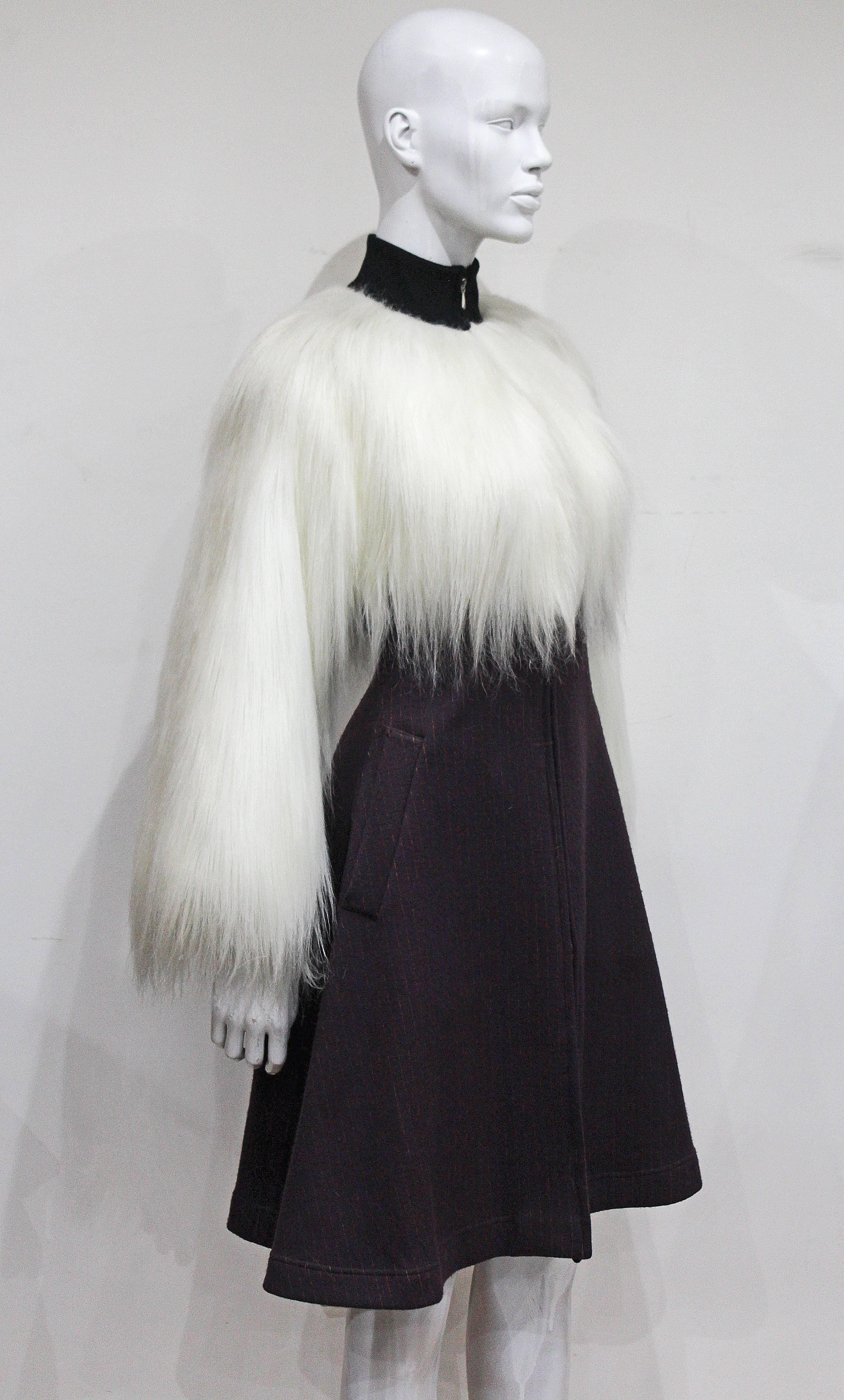 An incredible Jean Paul Gaultier fur dress coat from the year 1993. The dress features a long white fur on the bodice and sleeves, a woollen pinstripe flared skirt, metal zipper running through the centre and a black fitted polo neck. This dress is