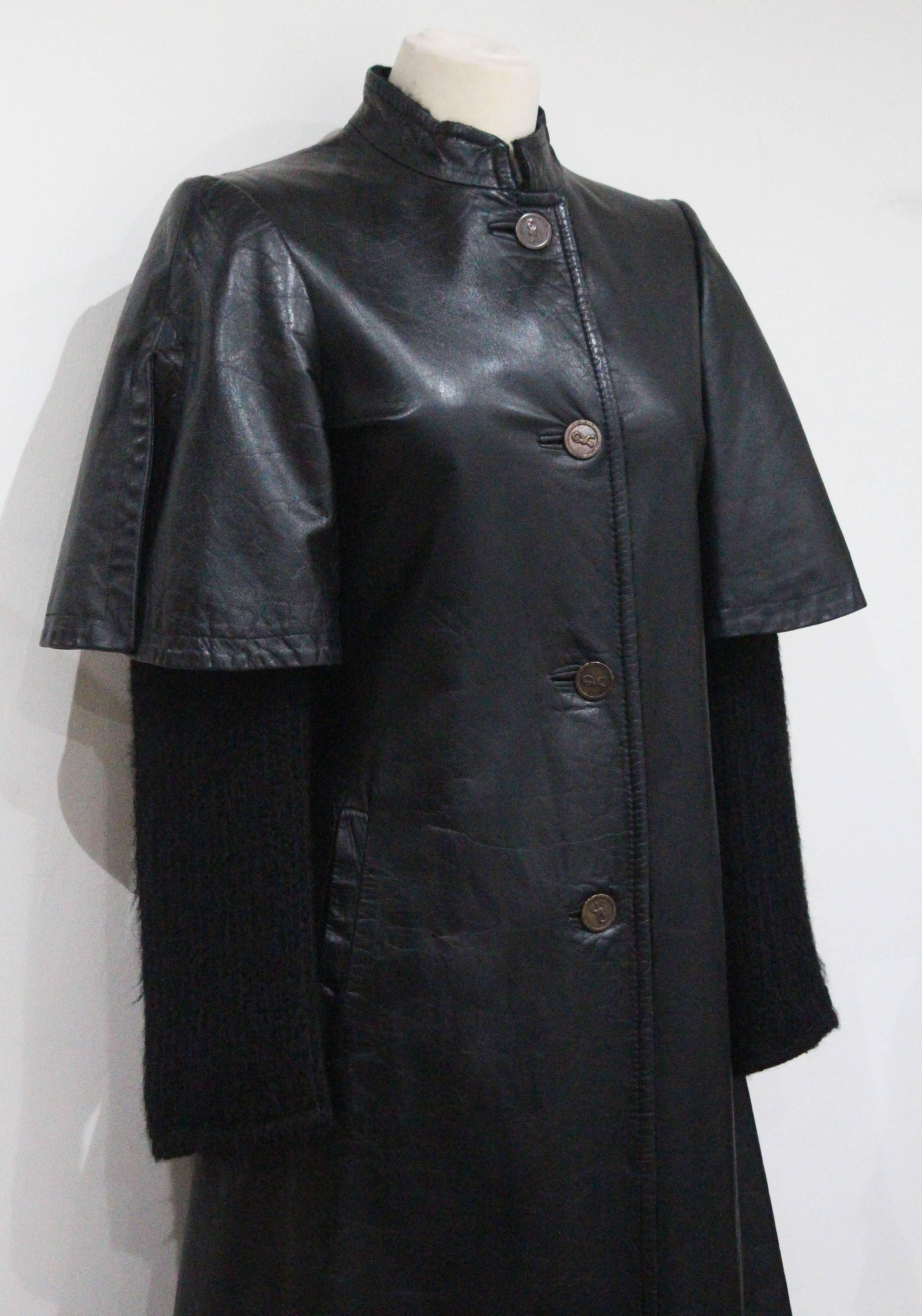 A Roberta Di Camerino black leather coat from the early 1970s. The coat is lined in knitted black wool and has knitted sleeves appearing underneath the leather cap sleeves with a slit. 

Made in Italy 

Size Small