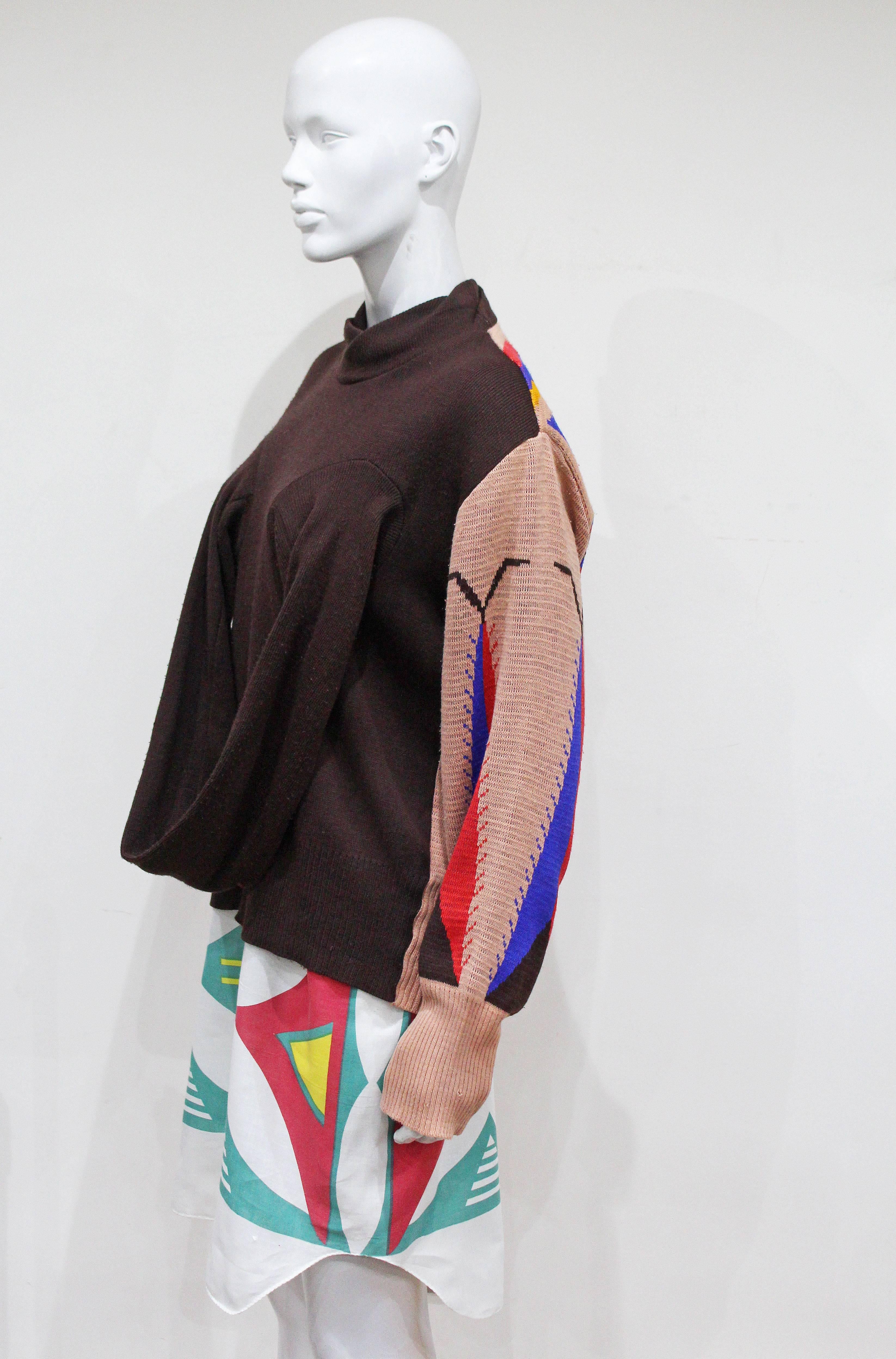 A rare World's End 'Savages' ensemble designed by Vivienne Westwood and Malcolm Mclaren for the Spring/Summer 1982 collection which was there second runway show. The ensemble features a knitted brown acrylic jumper with looped tube of fabric linking