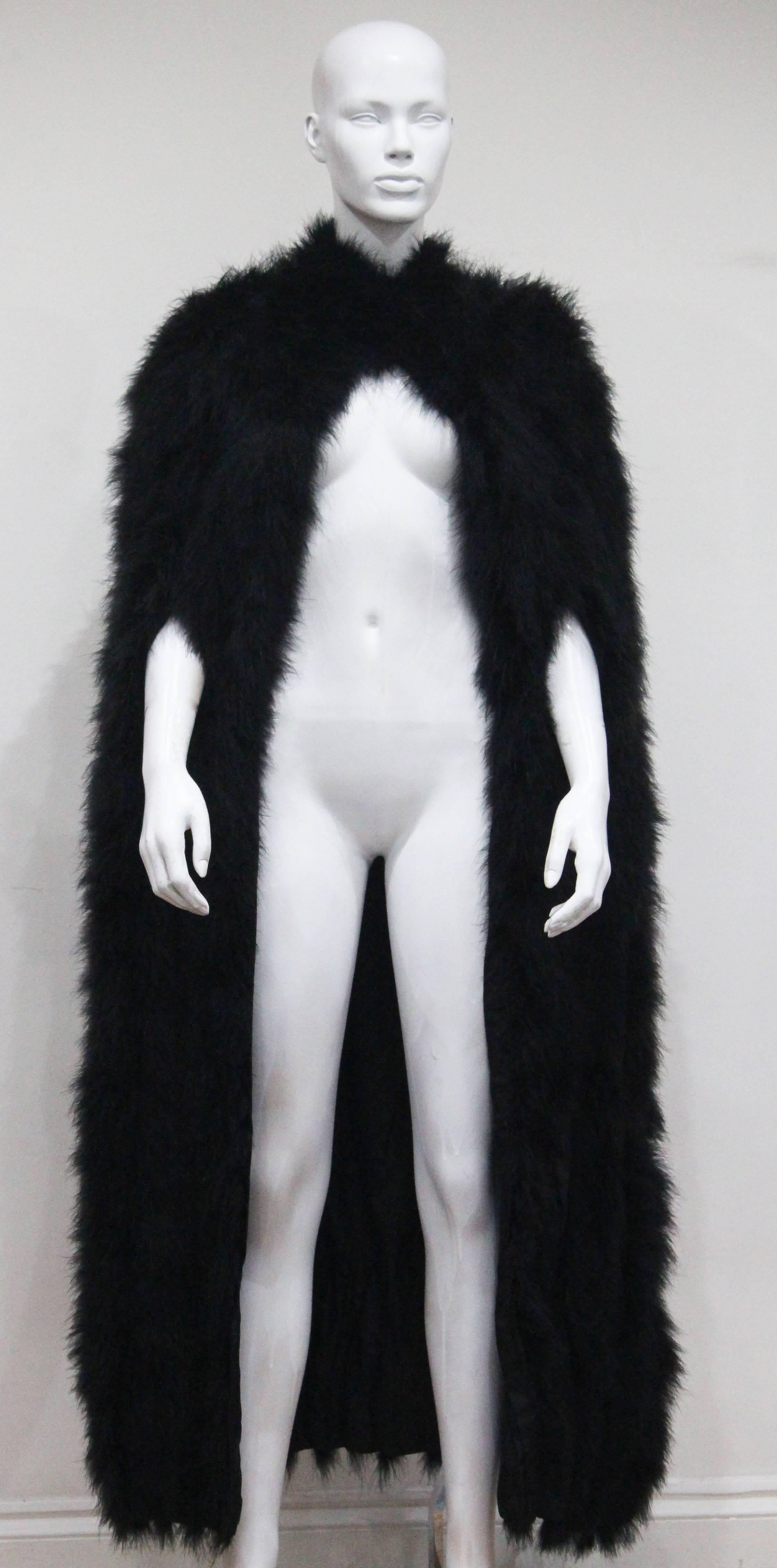 Black marabou full length cape made by Franka, which was a 1960s couturier in central London. The cape has two snap button closures around the neck and two arm holes. 
