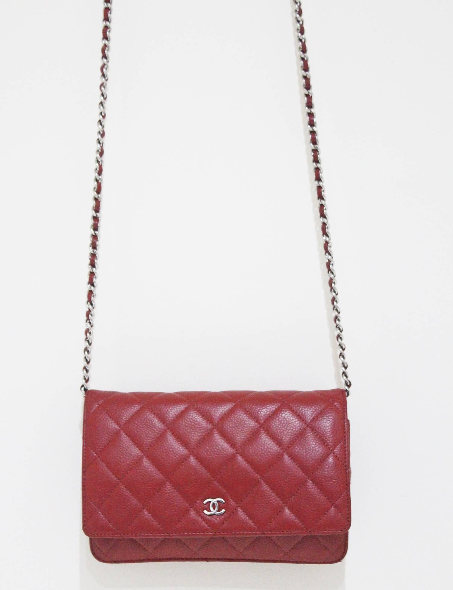 The Chanel WOC (wallet on chain) bag in red caviar leather with classic Chanel quilting. The bag features a snap button closure, silver woven chain cross body strap and open back pocket. The interior is lined in red caviar leather and red fabric.