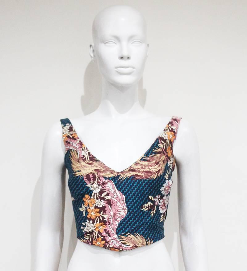 Presenting an exquisite Vivienne Westwood corset top artfully crafted from teal chevron-printed cotton, adorned with a captivating Japanese-inspired ukiyo-e print. This intricate artwork beautifully depicts florals, ocean waves, and ferns in a