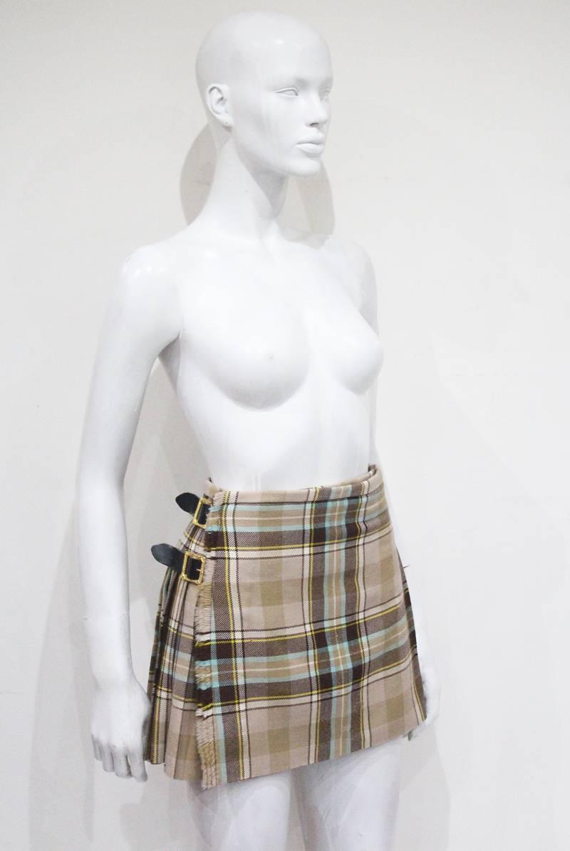 A rare Vivienne Westwood mini pleated mini skirt in the style of a Scottish kilt. The skirt features three gold Baroque style buckles and is made of 100% Scottish tartan wool. Kate Moss wore an identical skirt in a different colour for the Vivienne