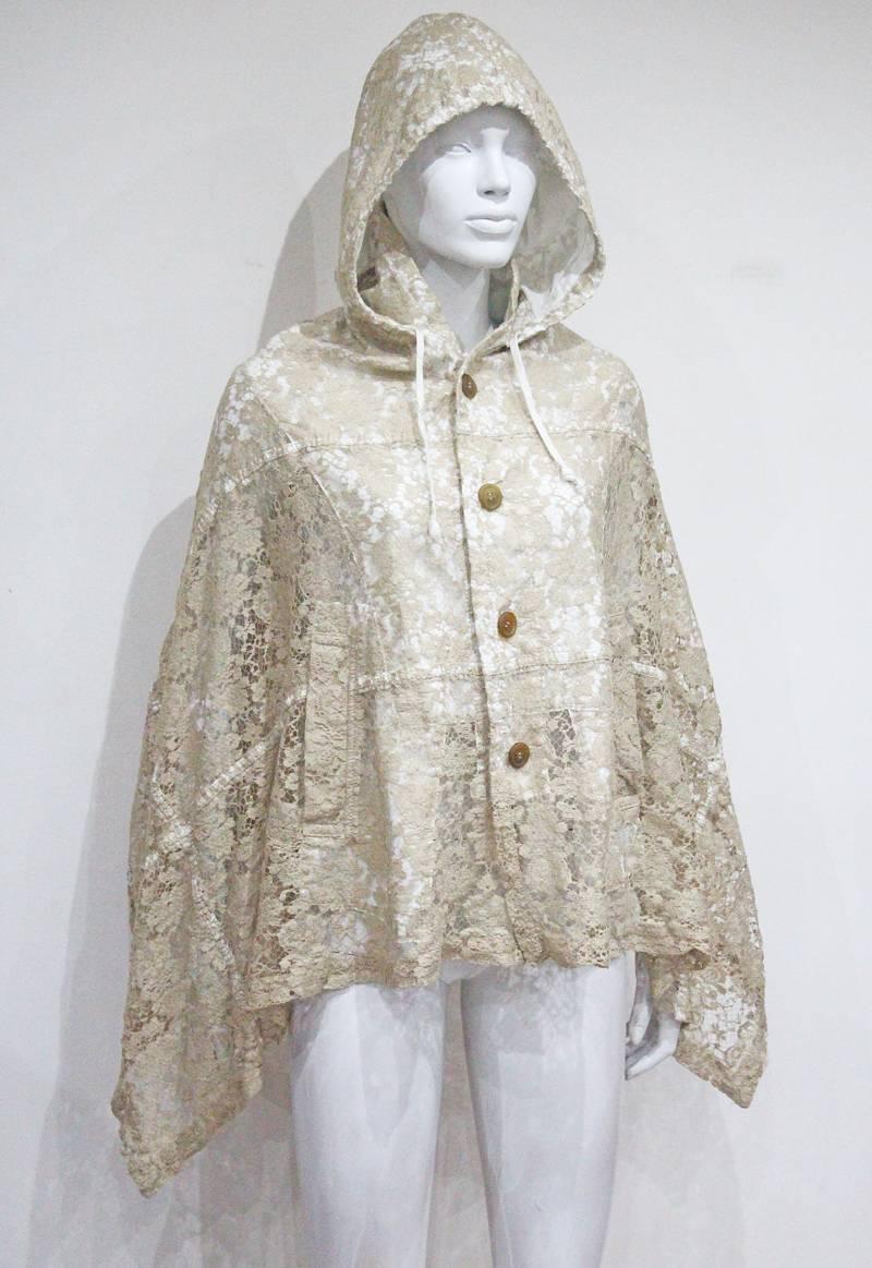 Comme des Garcons by Rei Kawakubo from the 1980s. 

Hooded lace poncho, shorter at rear, drawstring hood, four button closure, two front pockets, two arm slits, partially lined in white cotton.

Size: M 