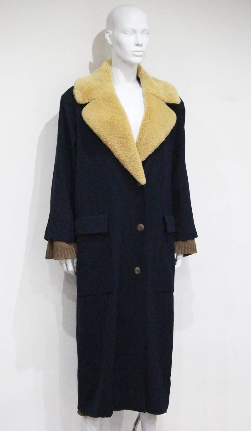 An early and rare Jean Paul Gaultier navy wool coat with oversized sheepskin collar and detachable knitted cardigan made in the early 1980s.

Size Fr 38 - It 42