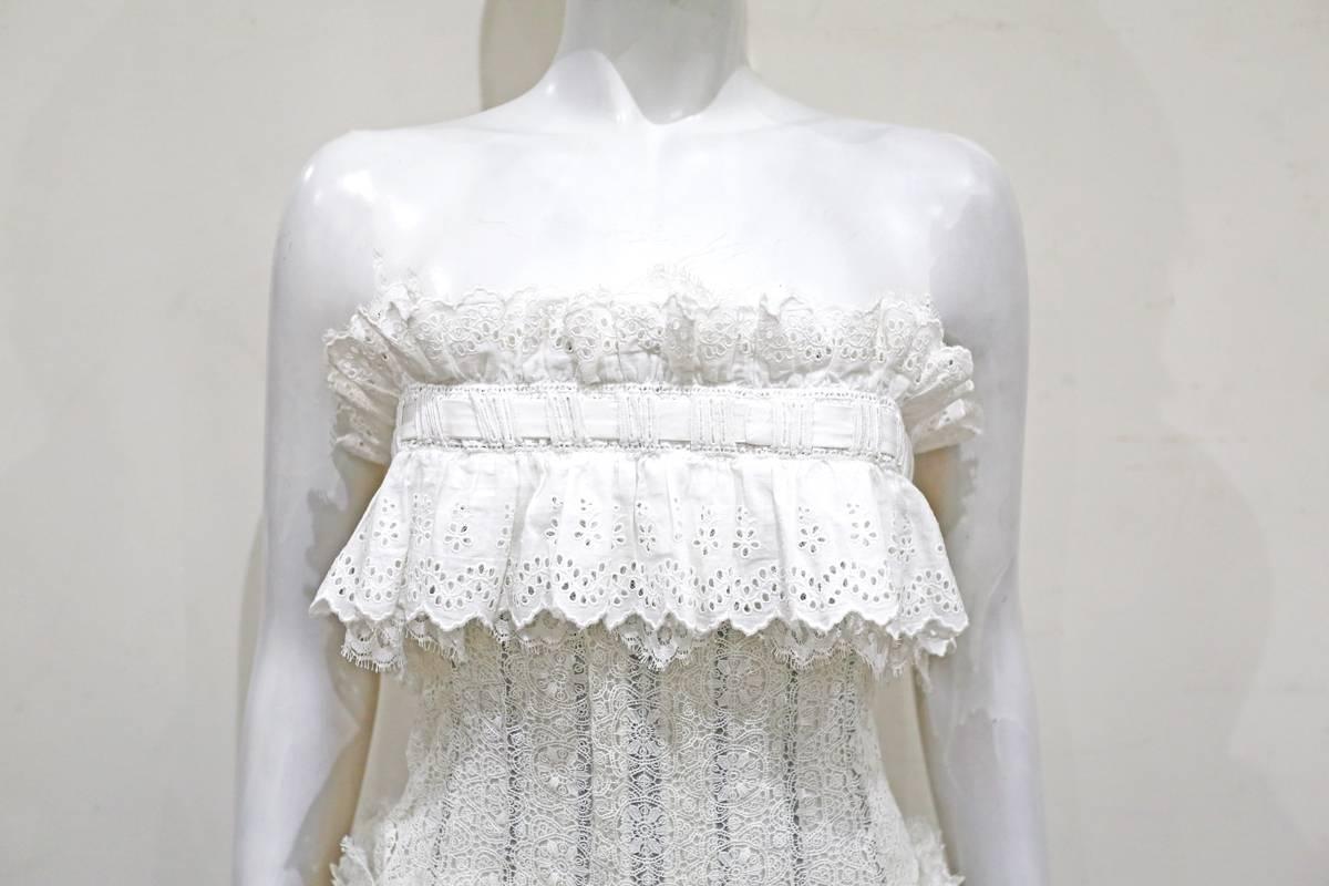 An absolutely stunning and elegant strapless white dress by Dolce & Gabbana made in the 1990s. The dress features heritage lace, hand clipped french lace and broderie anglaise lace through out and has three cotton bow fastenings. The bust and waist