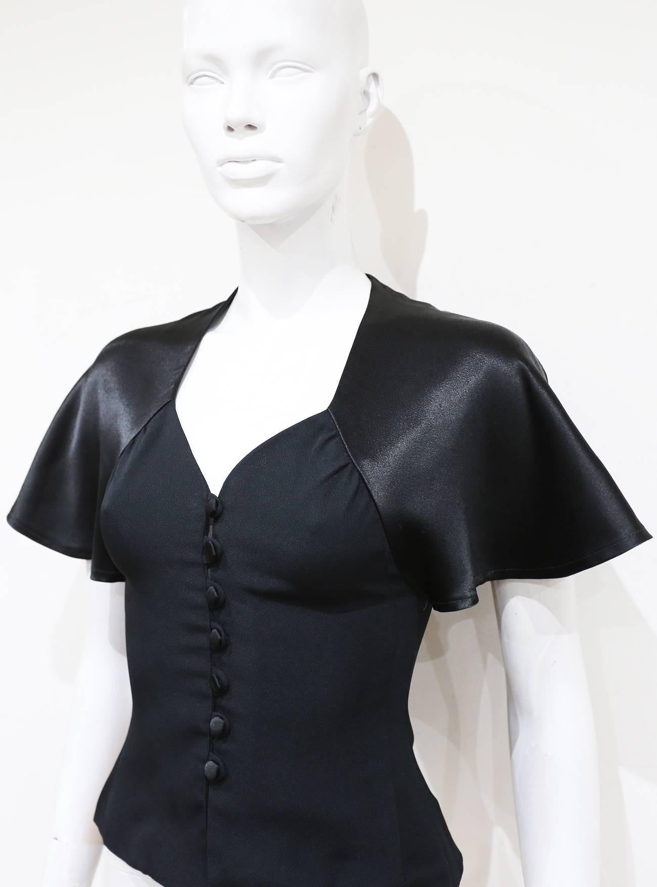 A beautifully cut Ossie Clark blouse from the 1970s. The blouse features a moss crepe bodice with fabric button closure and satin flared cap sleeves.

XS 