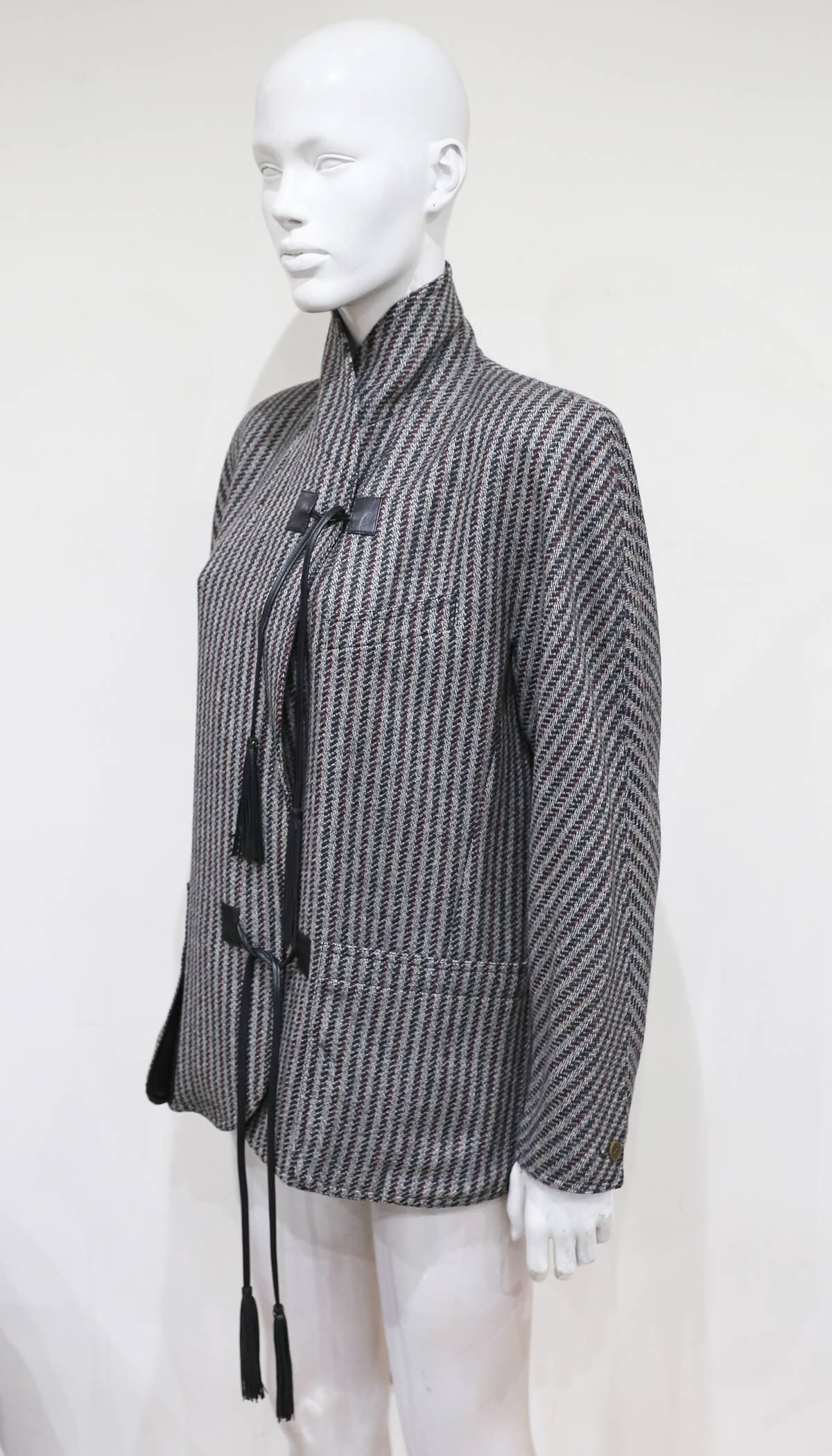 A fine women's tweed blazer by Gucci, circa 1980s. The blazer features leather assets on the front pockets, leather tassels on both closures and Gucci monogram silk lining. The jacket can be styled with a high neck or with a collar. 

Italian 42 -