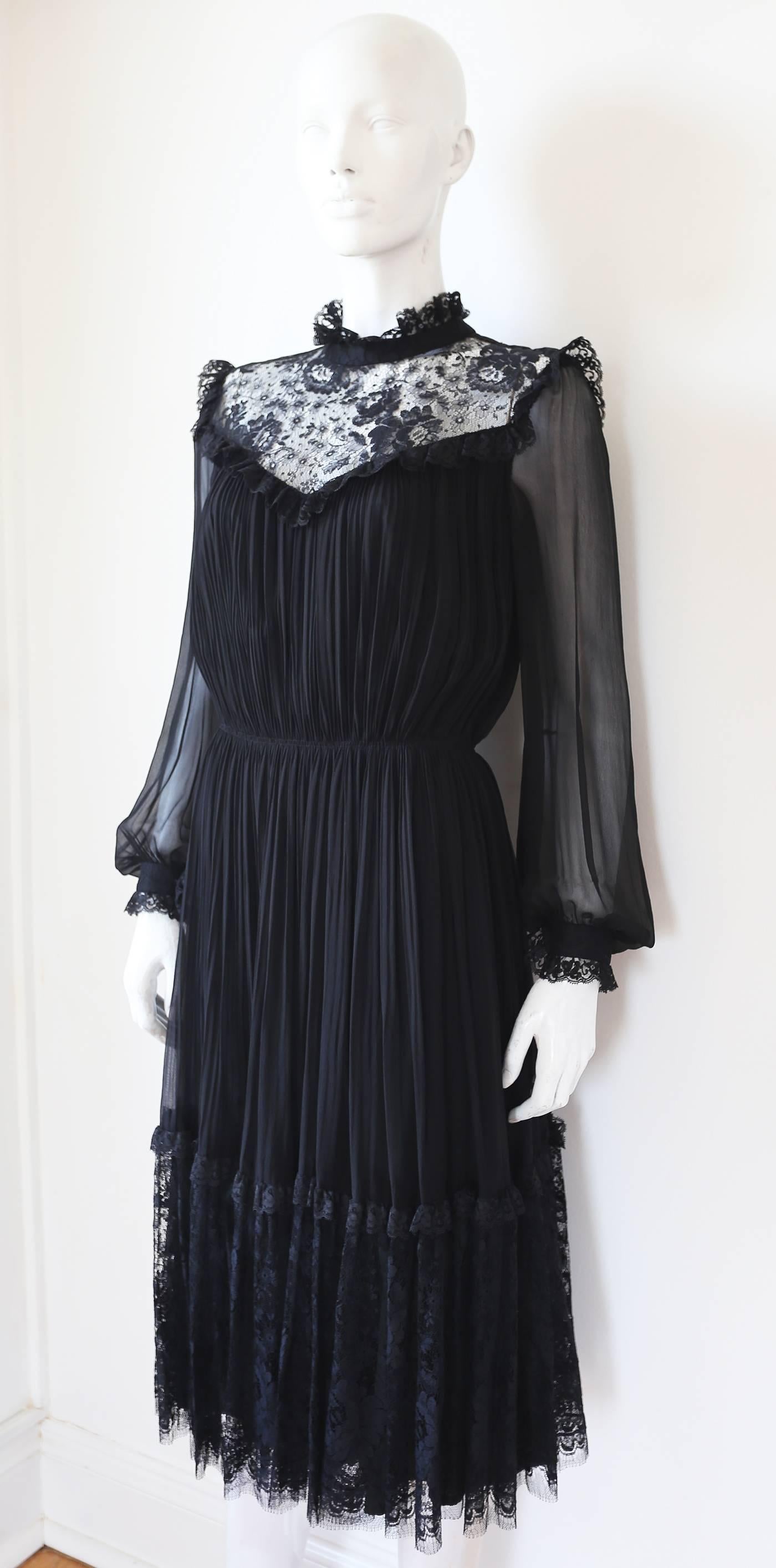 Hardy Amies silk chiffon evening dress, circa 1970s. The dress has a pleated bust and skirt, elasticated waist, a lace yoke, chiffon bishop sleeves and ruffled collar and cuffs.  

Hardy Amies, was an English fashion designer, and best known for