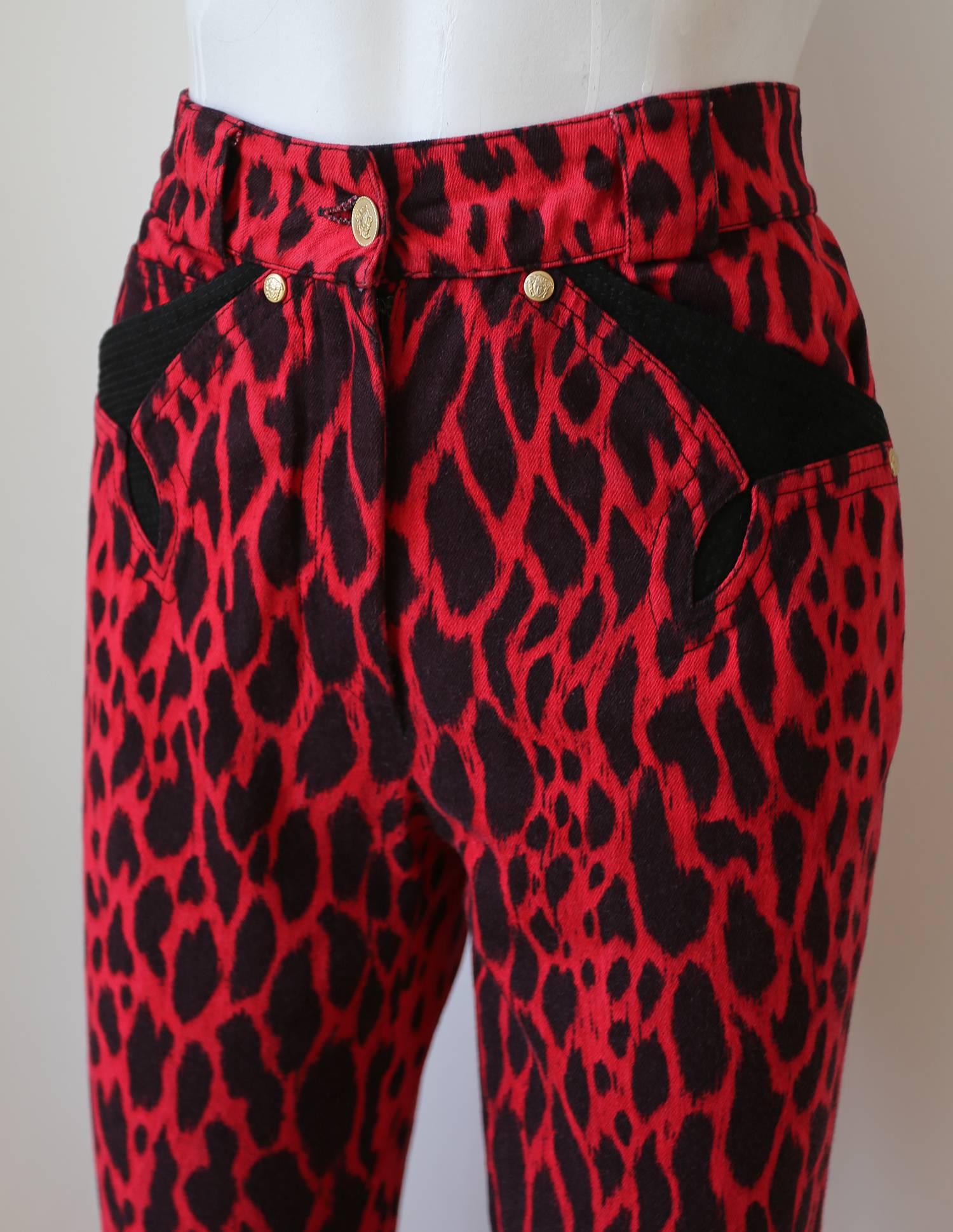 A pair of high waisted cigarette jean pants by Gianni Versace, designed for his Spring - Summer 1992 collection. The pants features an animal print throughout in red and black, gold-tone metal Medusa embossed buttons and studs, two front pockets,