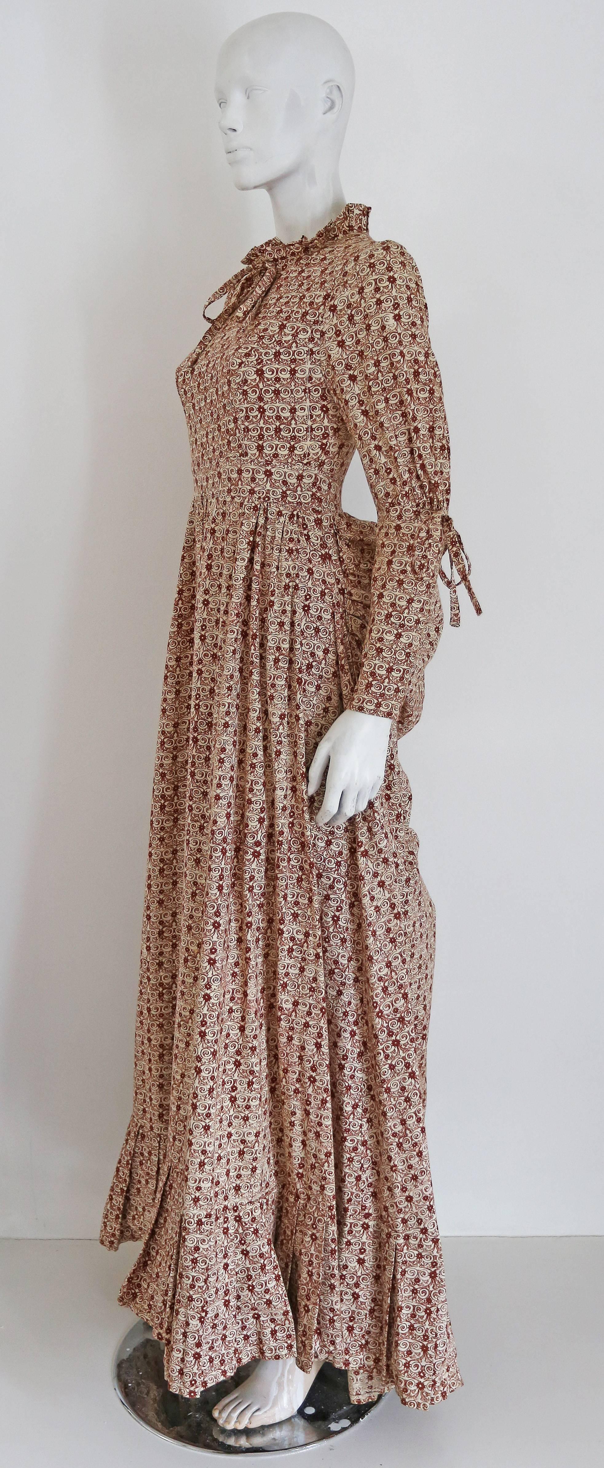 An extraordinary Laura Ashley evening dress with bustle, circa early 1970s. The dress is in a fine cotton with screen printed floral print. 

Size: Eu 38-40 10-12
Shoulder to shoulder - 18