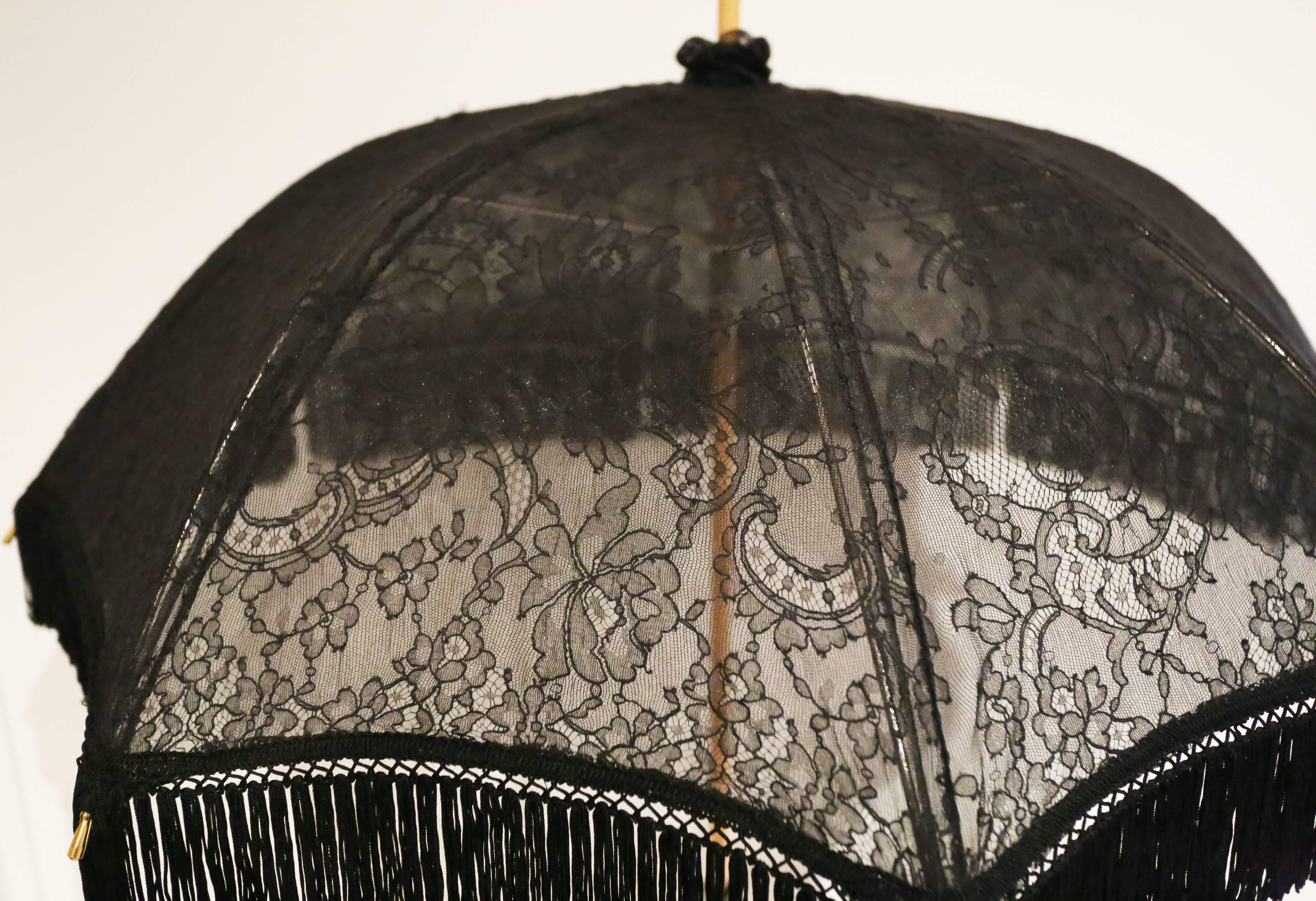 A one of a kind Vivienne Westwood black lace parasol, circa 1990s. The parasol has a fringed trim, wooden handle and tassel. 

