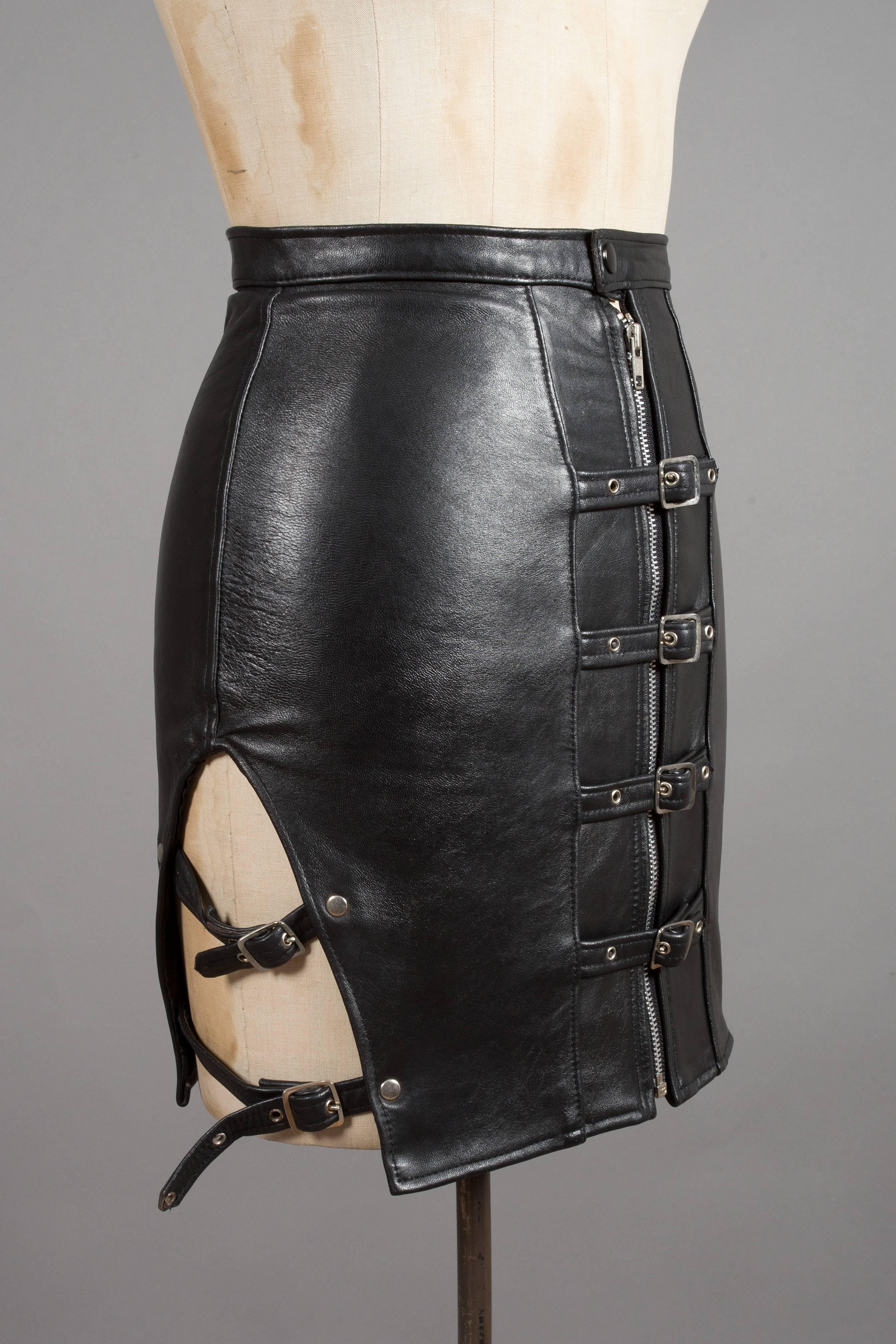 Original 1970s punk black leather mini skirt with side cut outs, large metal zipper closure and multiple buckle fastenings throughout. 

Waist 28