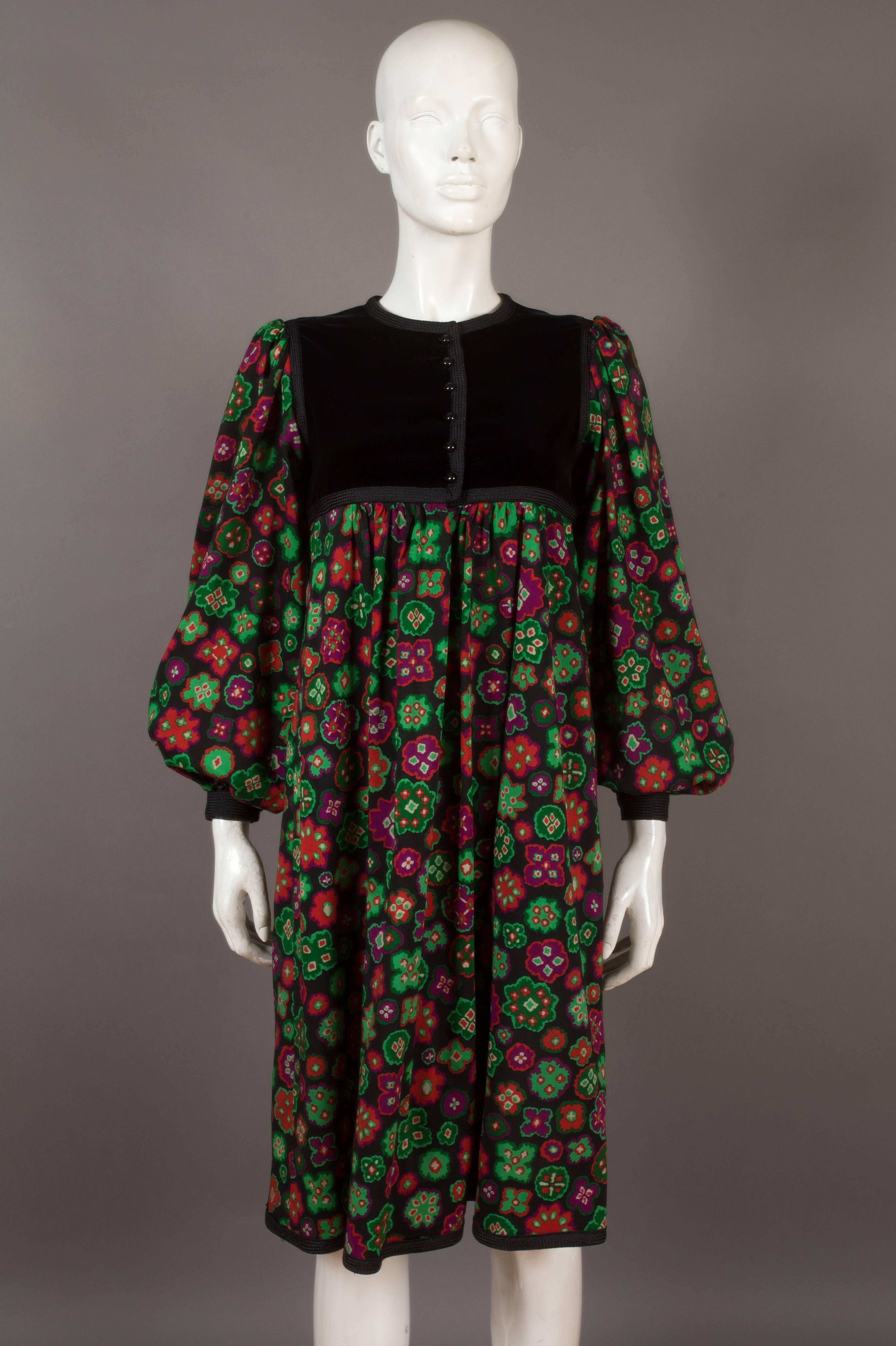 A Yves Saint Laurent 'Rive Gauche' folk dress, circa 1976. 

Black velvet bodice yolk, braided trim, button closure, pleated bishop sleeves, two hidden pockets, full pleated skirt falling below the knee and a vibrant folkloristic floral print on