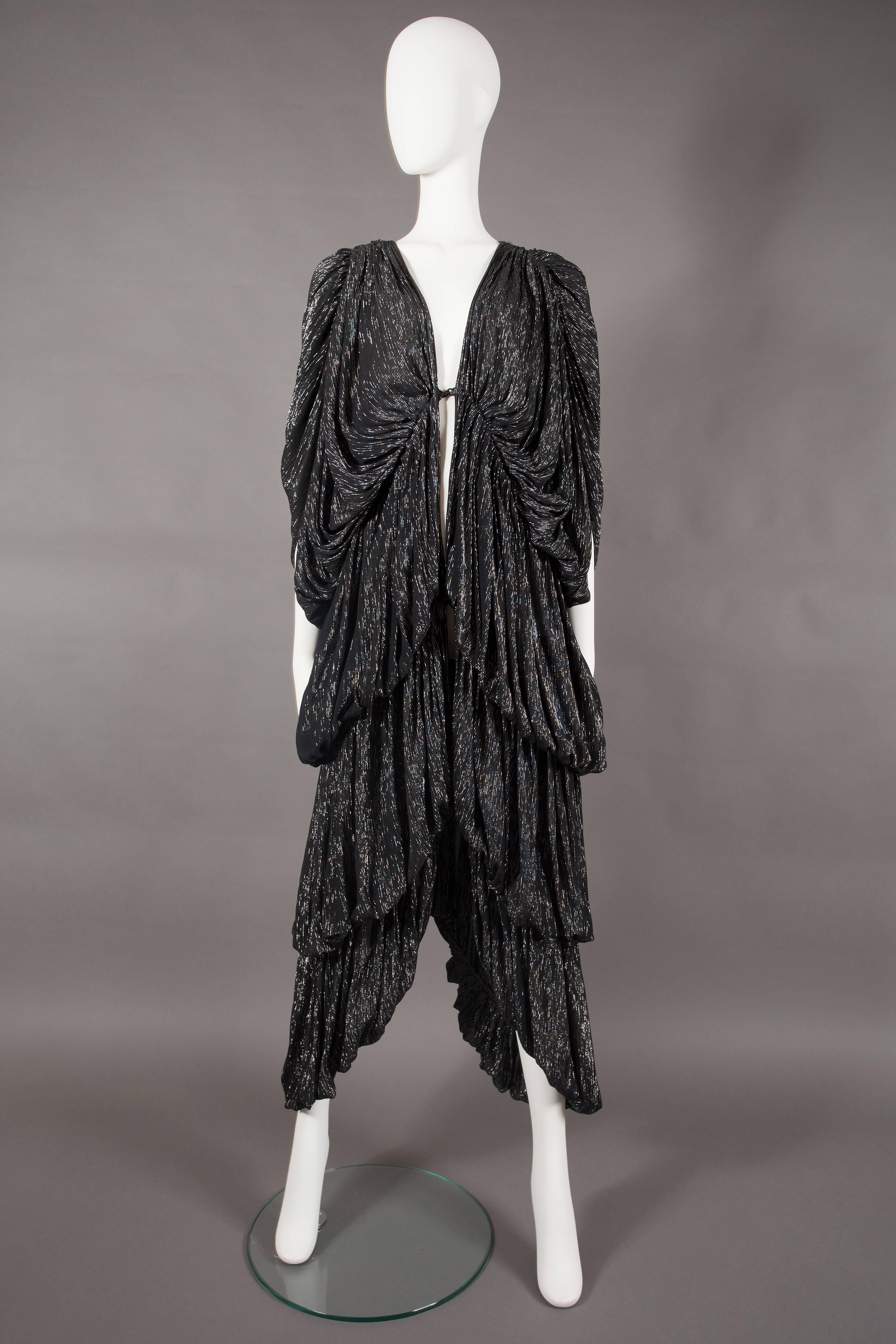 A rare Norma Kamali tiered evening dress, circa 1977. 

Three hook and eye closures on front opening, black with silver metallic stripes, tiered design with heavy pleating throughout. 

