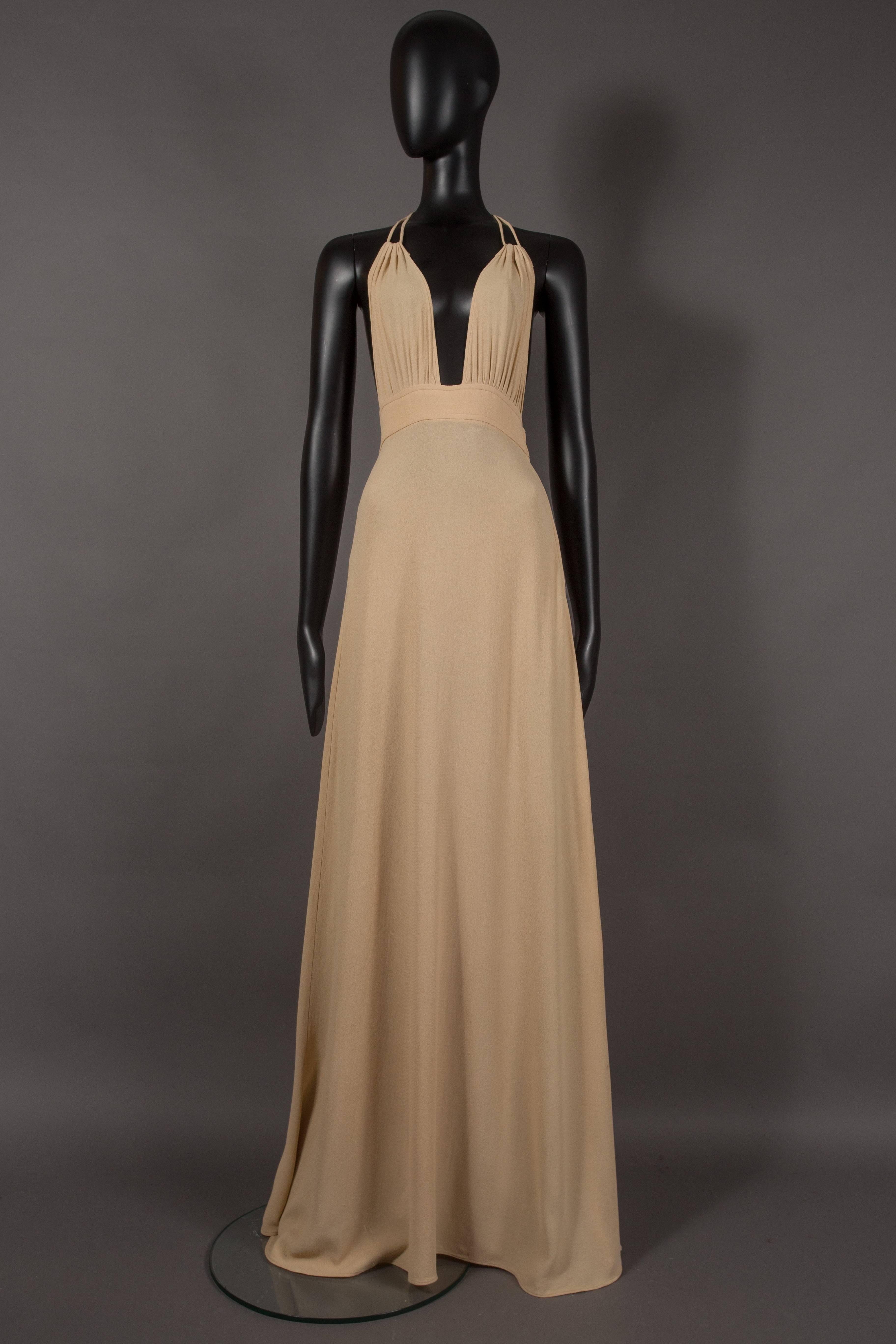A rare Quorum champagne moss crepe evening dress, circa 1960s. Open back, metal zip closure, halter neck, drawstring pleated bust and full length flared skirt

Alice Pollock founded the Quorum boutique in 1964. In 1965 Ossie Clark started working