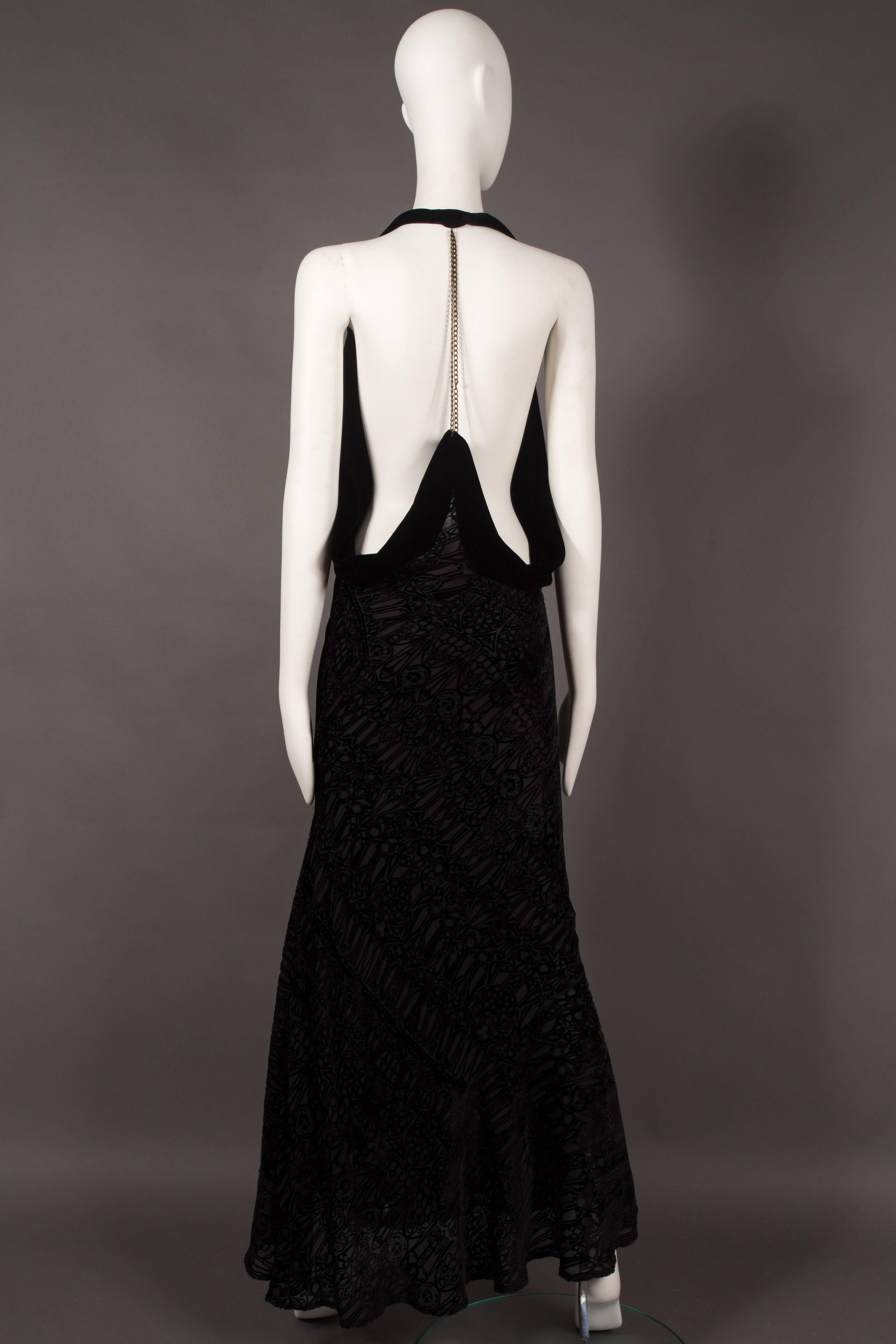 Alexander McQueen black silk devore bias cut evening dress, circa 2004. 

Velvet halter neck, open back, chain hangs from the collar at rear and attaches to the skirt, cowl neck, and ruffled skirt. 