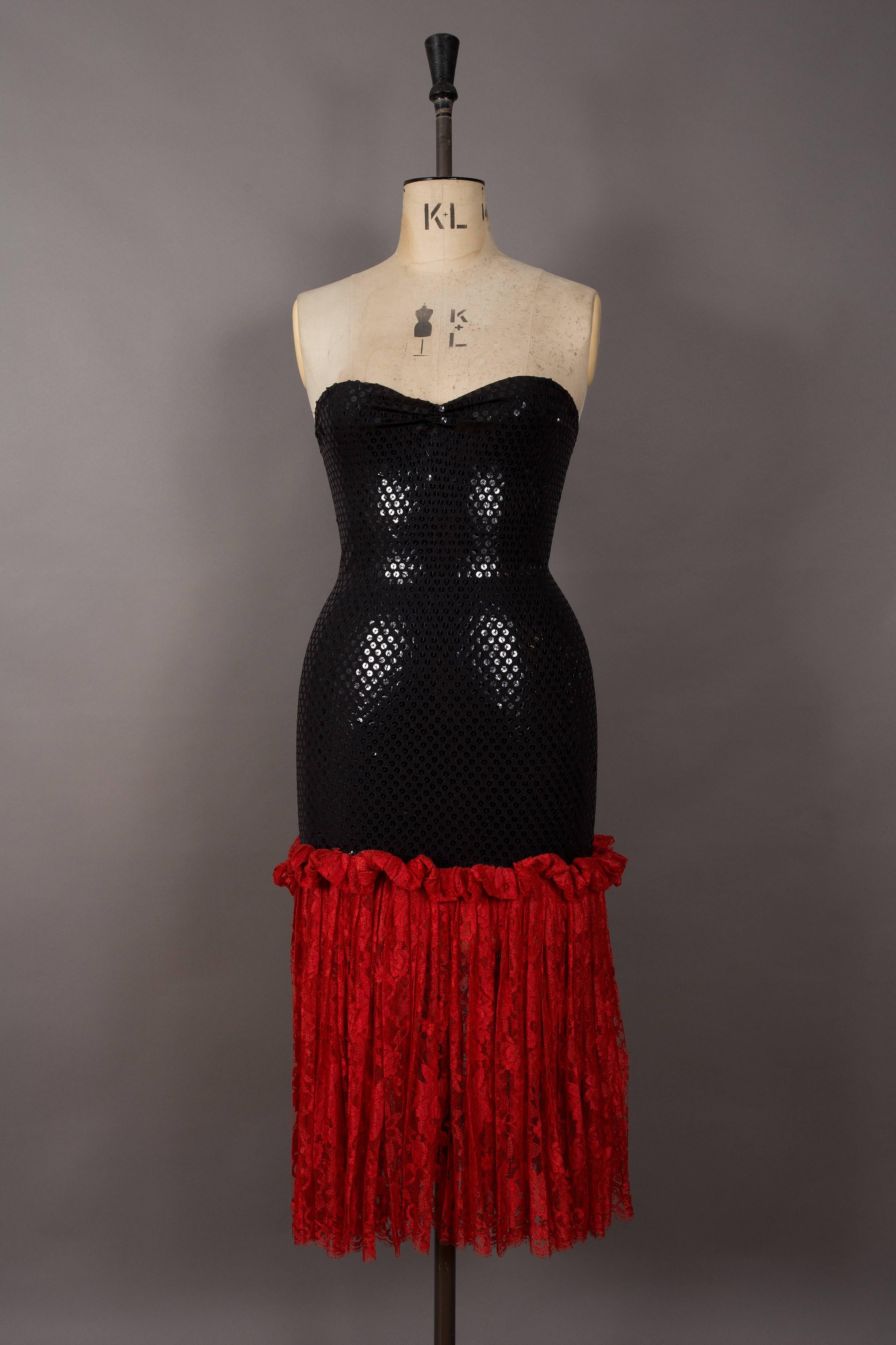 Bastet strapless sequin cocktail dress, circa late 1970s. Black stretch knit decorated in sequins and pleated semi-sheer red lace skirt.