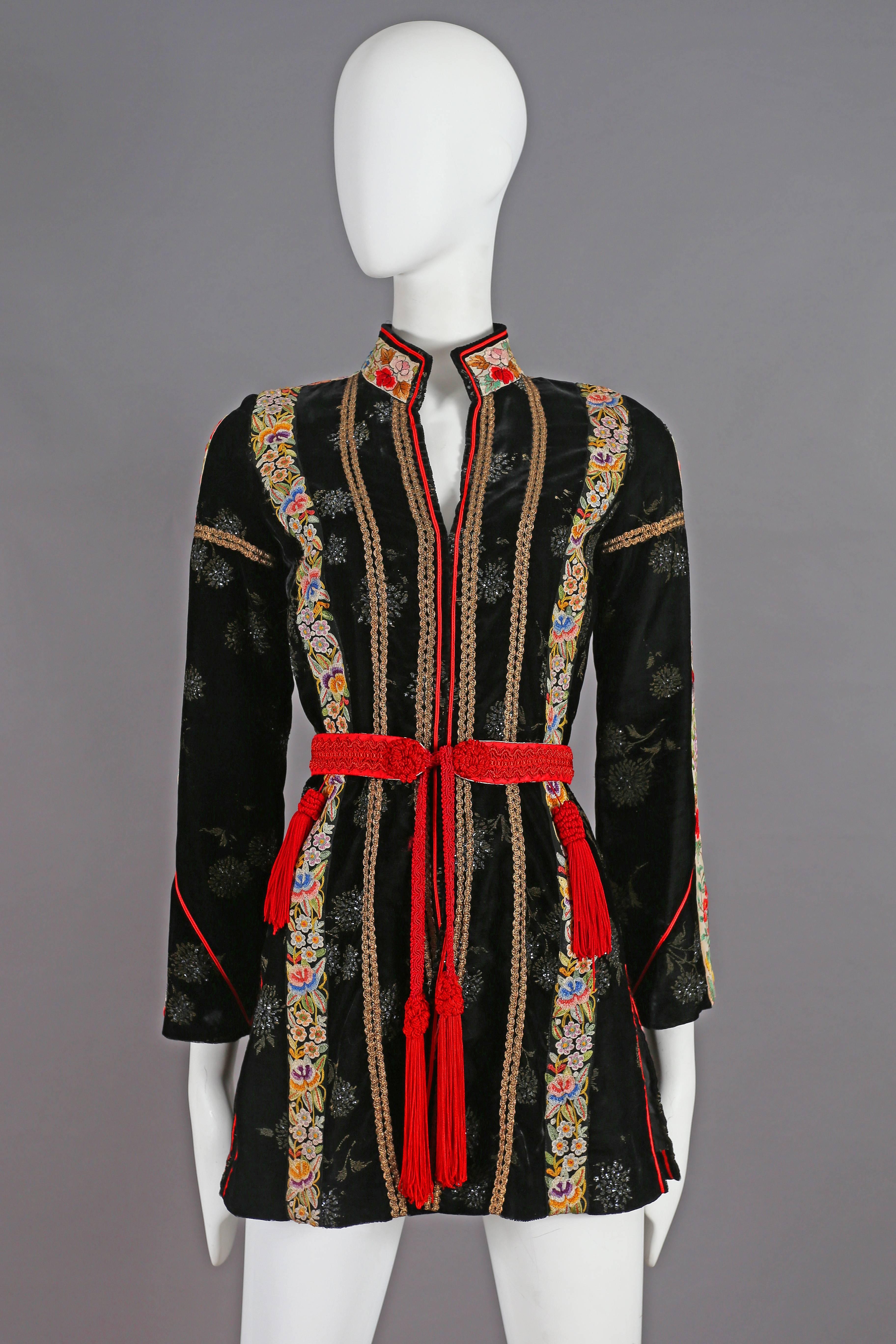 Exquisite and rare Thea Porter Couture black velvet evening jacket with intricate floral embroidered panels, gold lame piping and red waist belt with five tassels. 