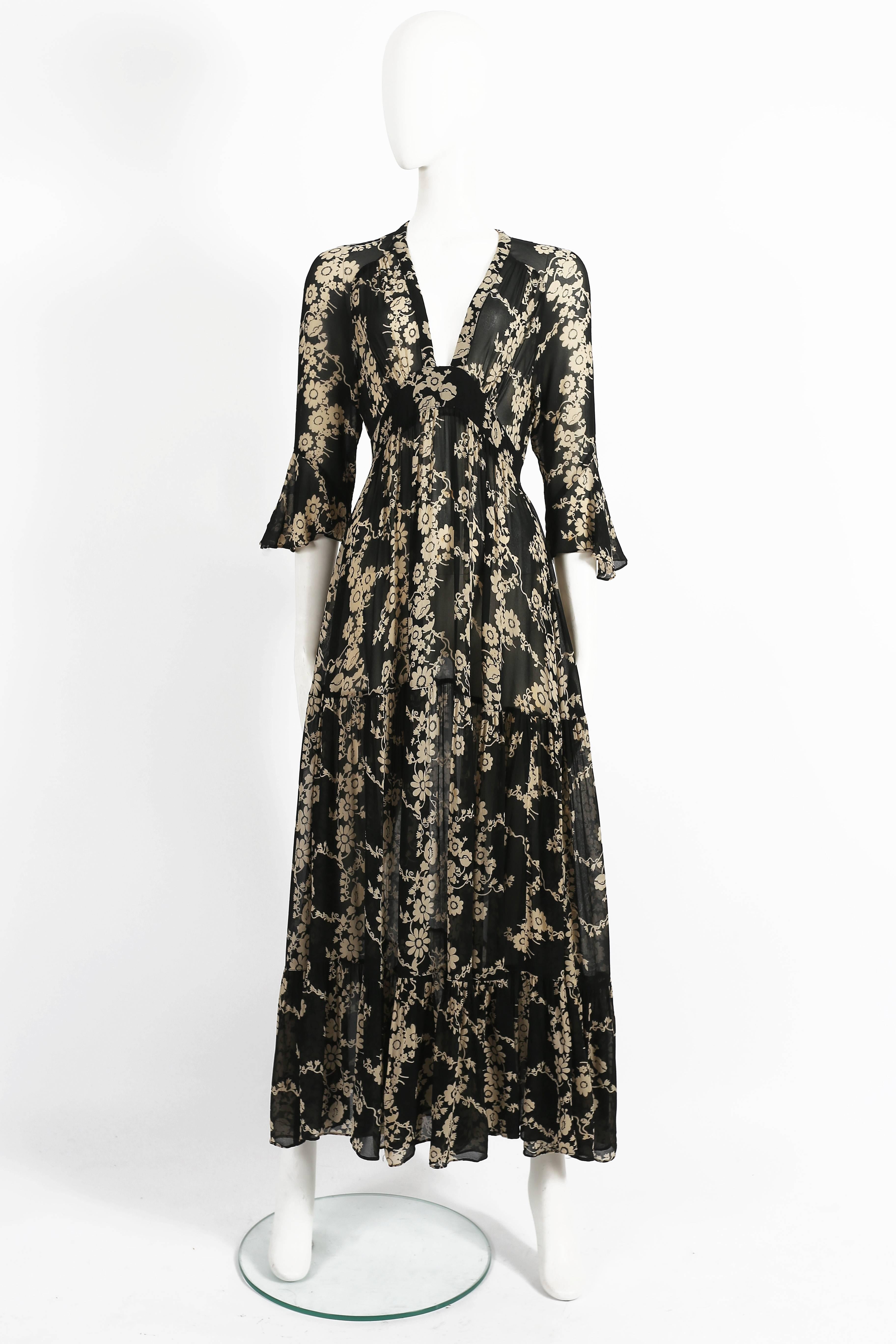 Exquisite Ossie Clark 'Soviet Rose' chiffon gown, circa 1972. The dress is constructed in a Celia Birtwell printed chiffon fabric with cream blooms on a black ground, v-neckline, front and back and ties at rear neck and the skirt falling in three