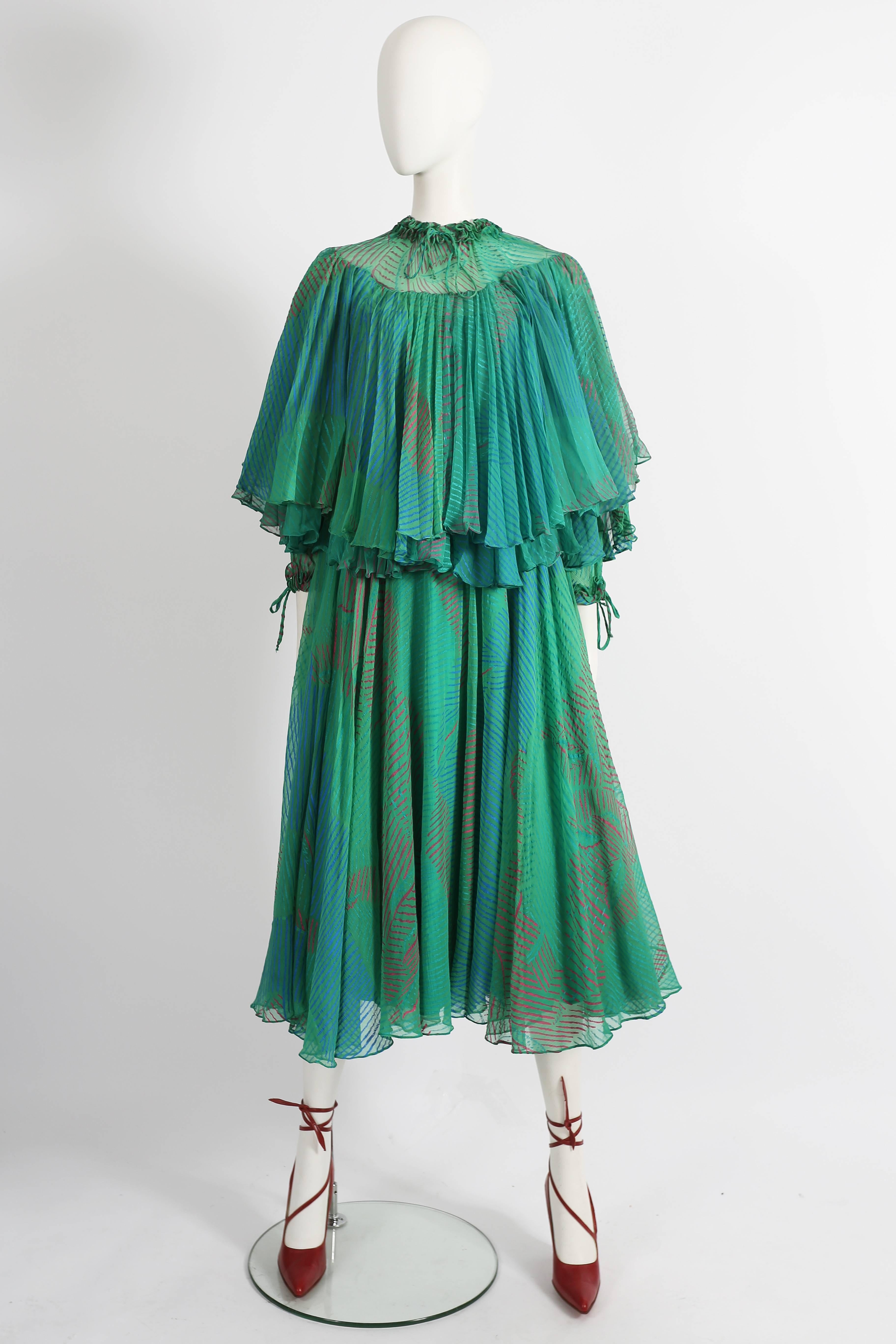 Ossie Clark and Celia Birtwell silk chiffon evening dress, couture line, circa 1976. Drawstring fastenings at neck and cuffs with ruffled trim, semi-sheer yoke, two pleated panels around the bust and full skirt with silk lining. 

The dress is