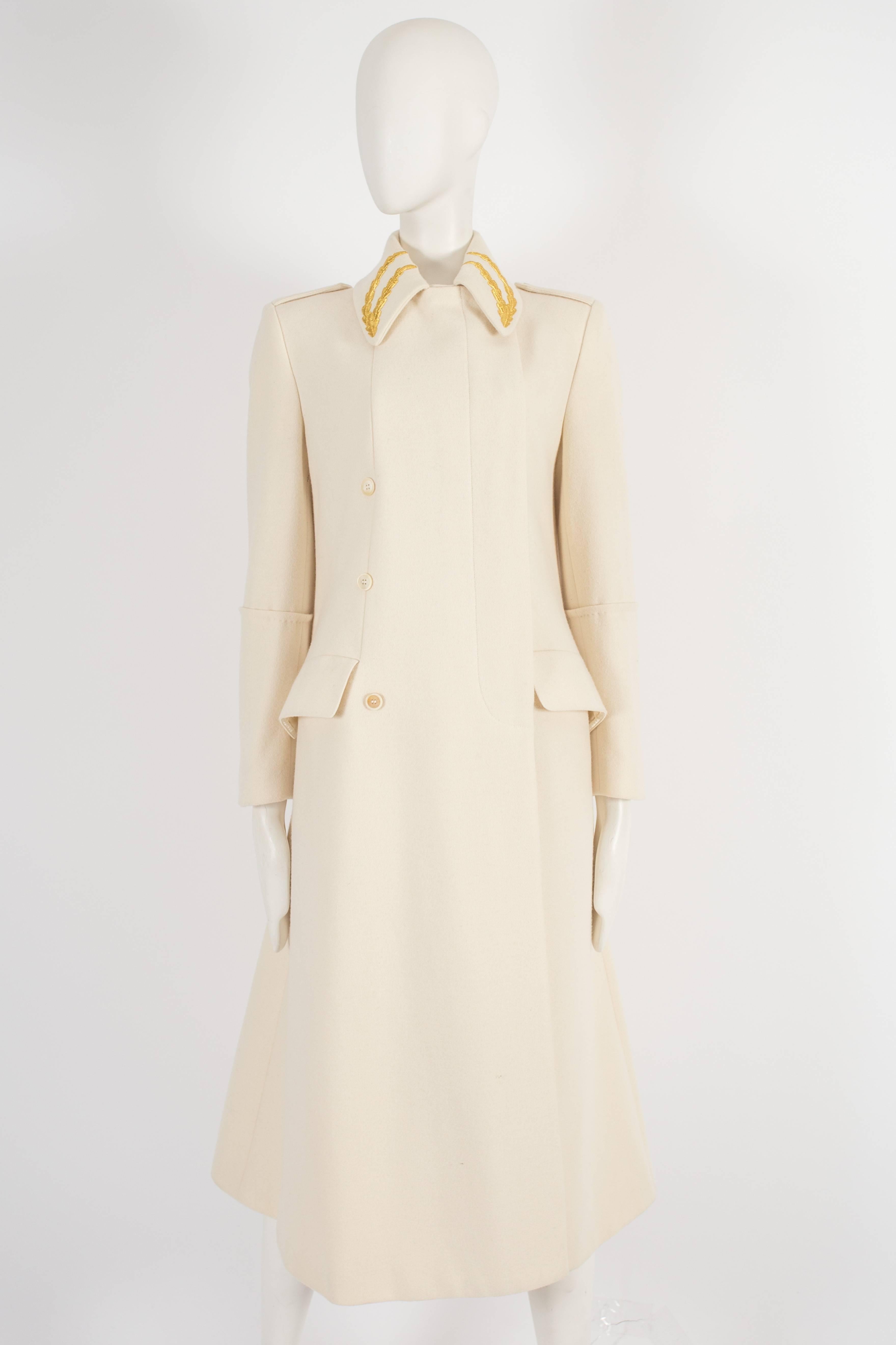 Alexander McQueen tailored cream coat, circa 1990s. The coat is constructed in a heavy wool and features two gold motifs on each collar and hidden button fastenings.