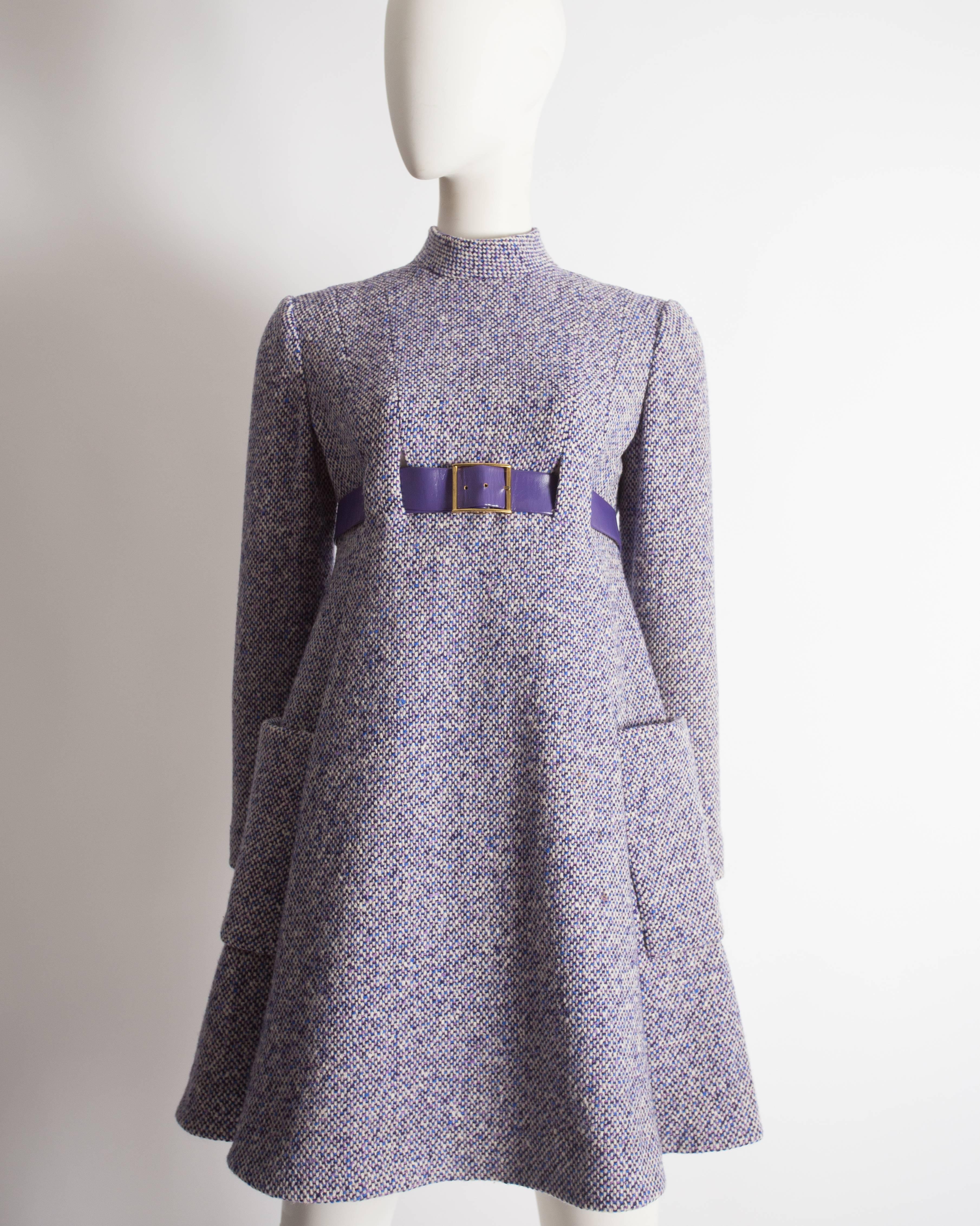 Geoffrey Beene mini dress constructed in wool tweed with a purple leather belt, box pleated skirt, two open front pockets, zip fastening at the rear and silk-satin lining. 

Circa 1965

