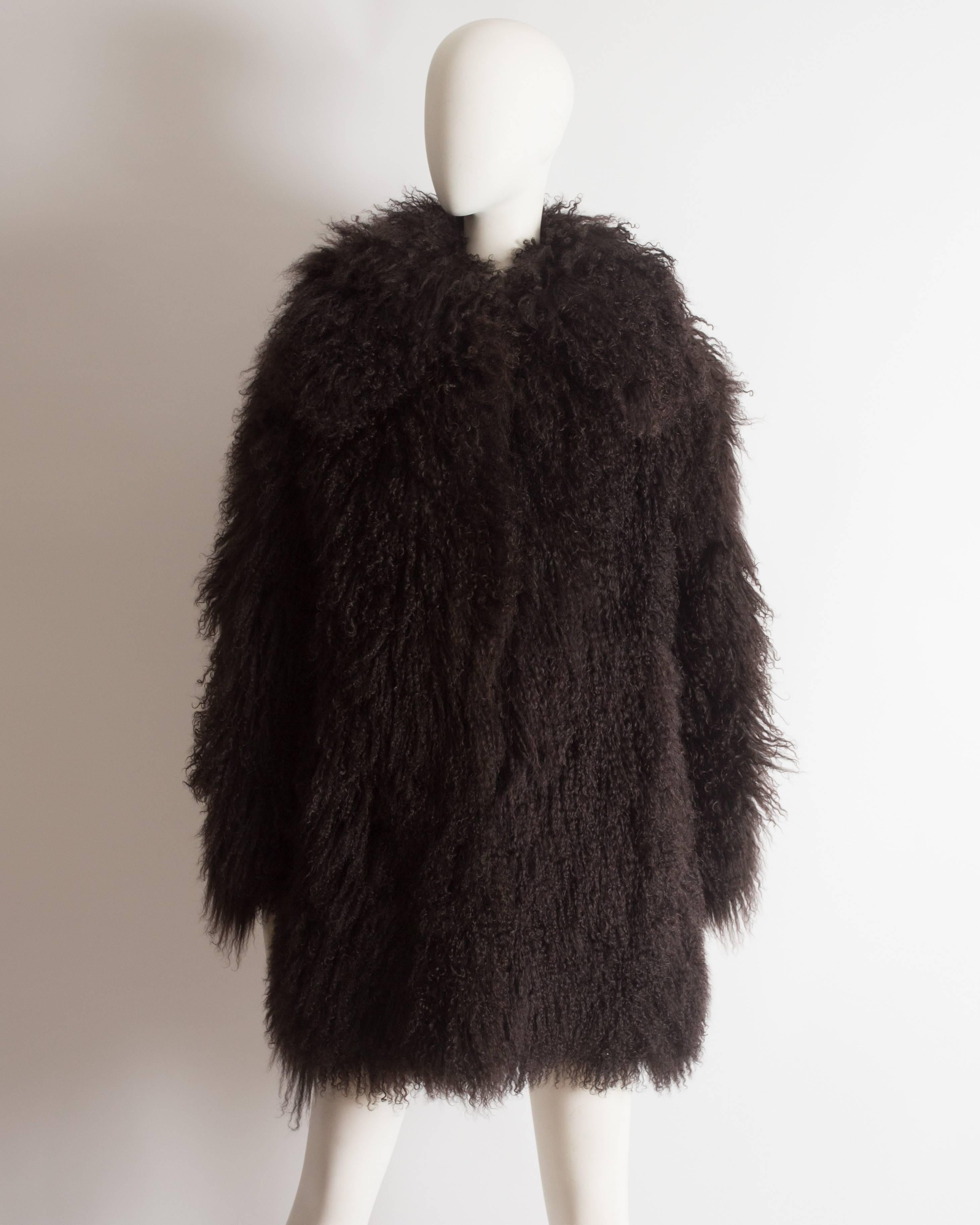 Alaia Mongolian lamb coat with oversized collar, hook-and-eye fastenings, and two front pockets. 
